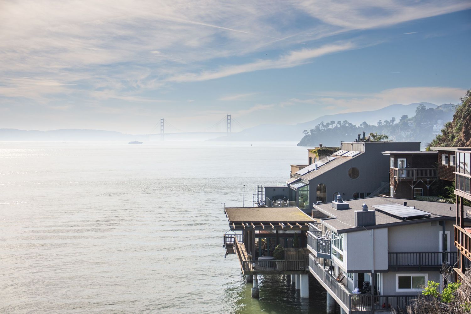 Coastal luxury homes with mountain views and clear blue skies in the background.