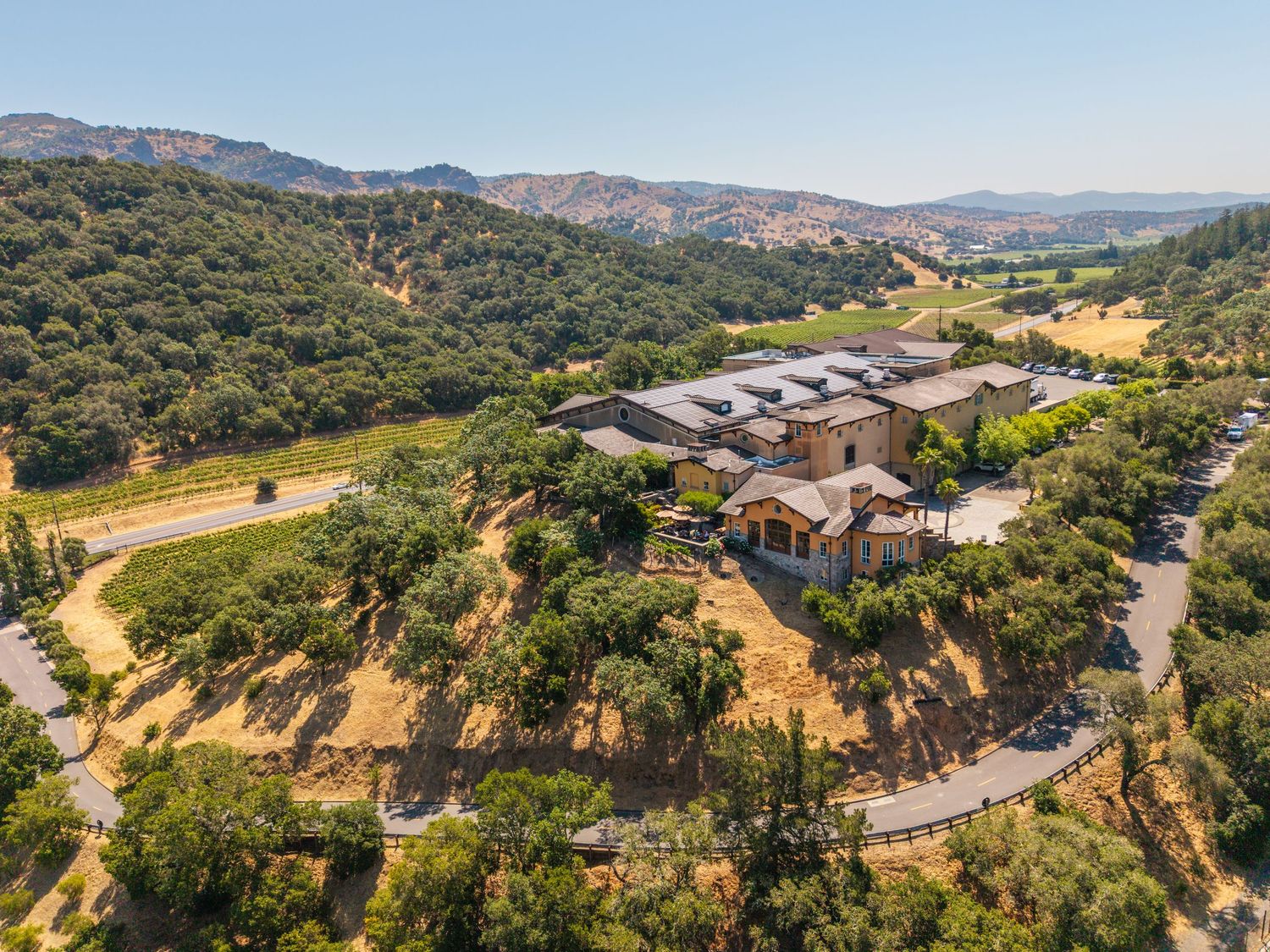 Aerial view of a winery estate nestled among oak trees and vineyards in a scenic California valley.