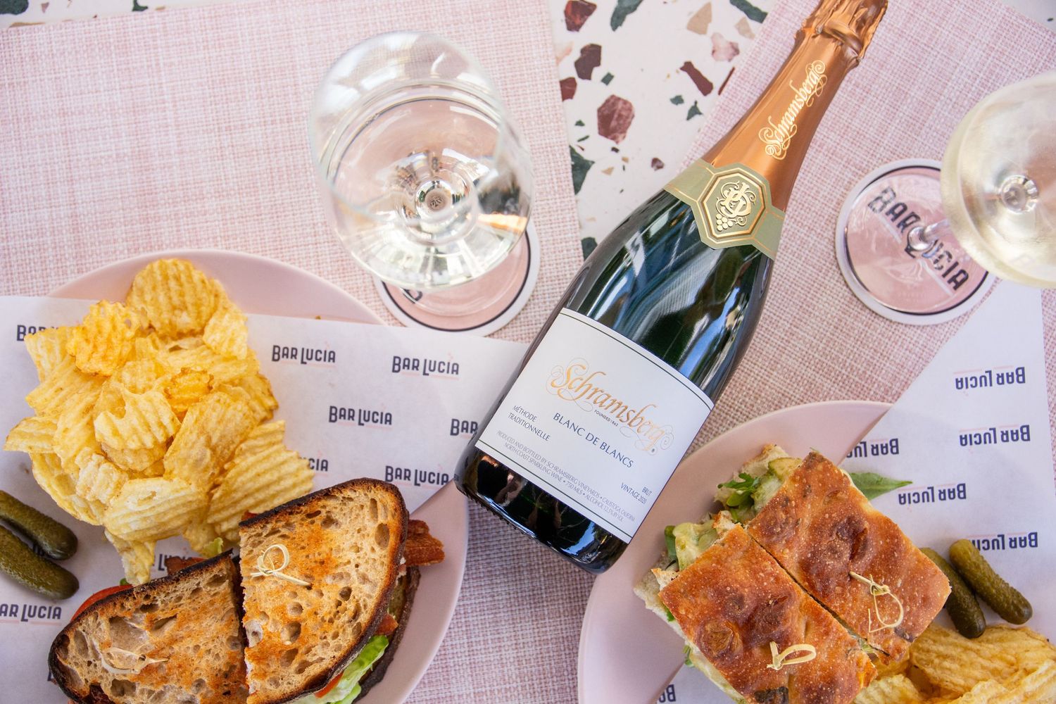 Assorted appetizers and champagne bottles served on pink table settings.