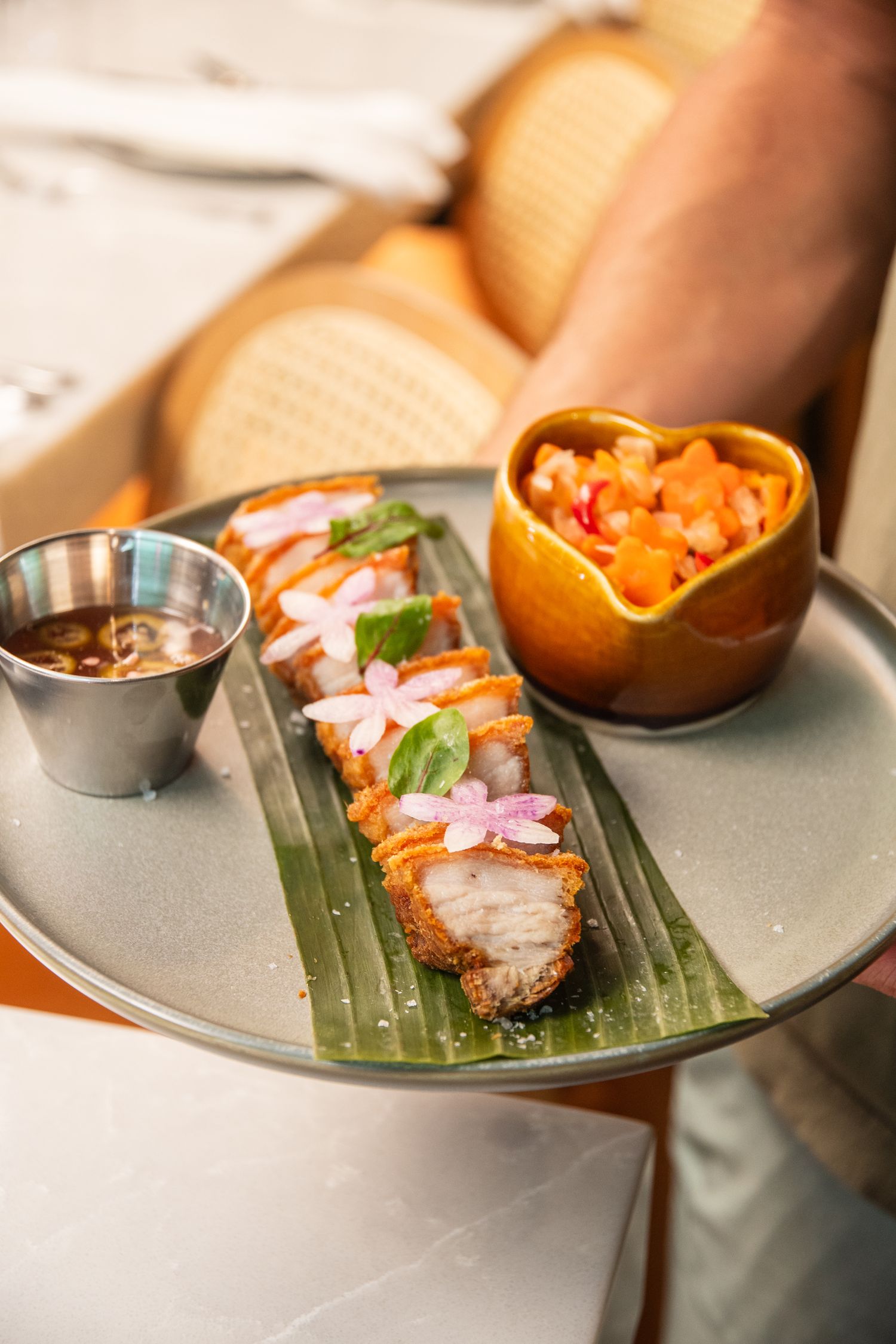 Asian-inspired seafood dish served on banana leaves with vibrant garnishes and sauces.