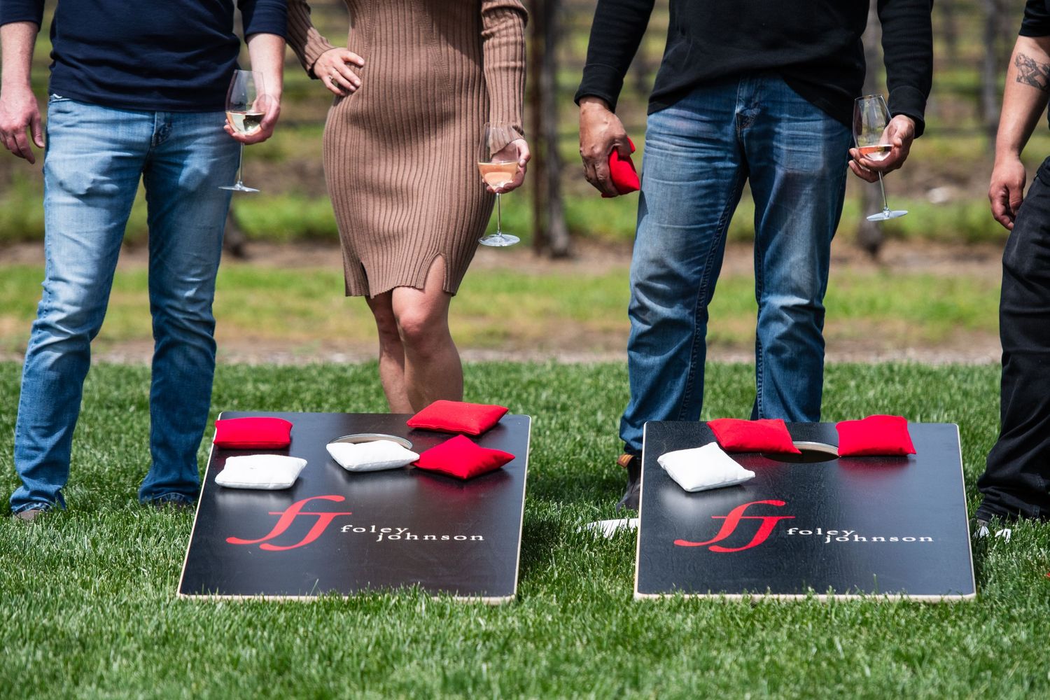 Cornhole game boards set up on grass lawn at outdoor winery event.