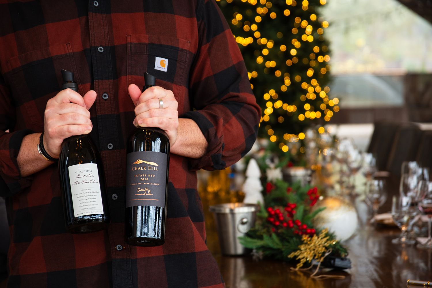 Wine bottles being presented against a warm background with festive holiday lights.