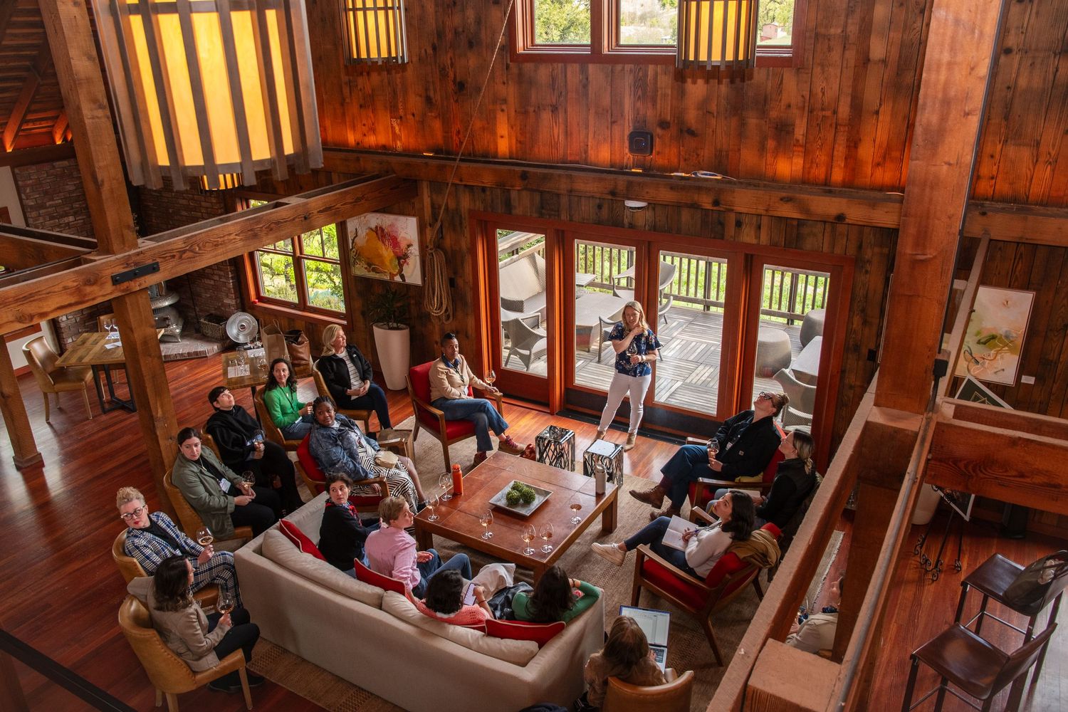 Interior view of a rustic barn venue with wooden beams and large windows during a gathering.