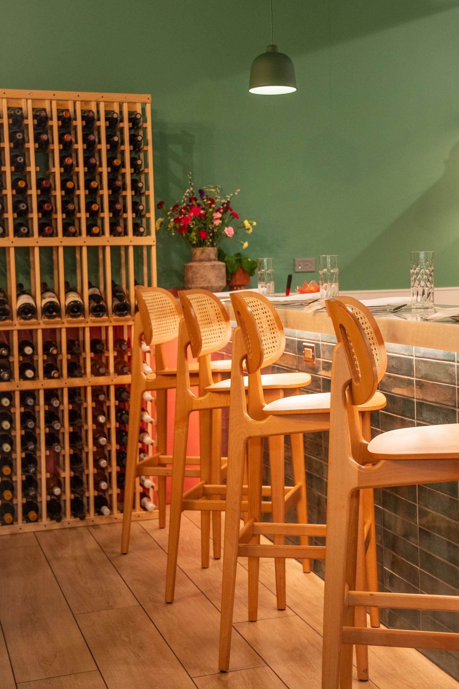 Wine cellar dining room with wooden chairs and green walls.