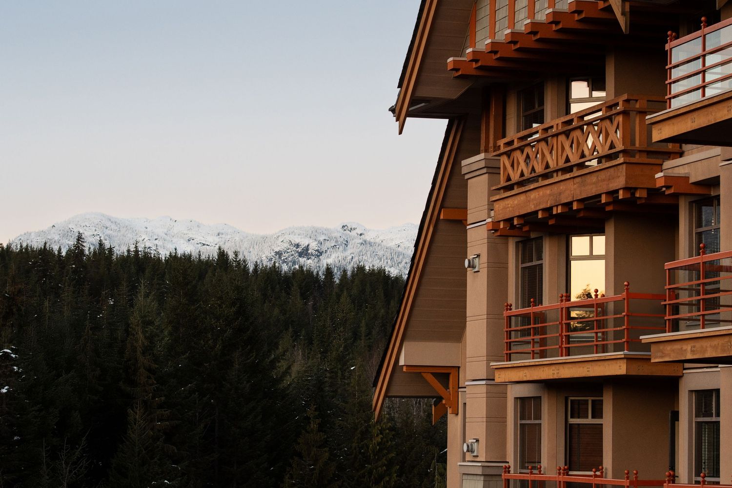 Mountain lodge exterior with wooden balconies against a backdrop of snow-capped peaks.