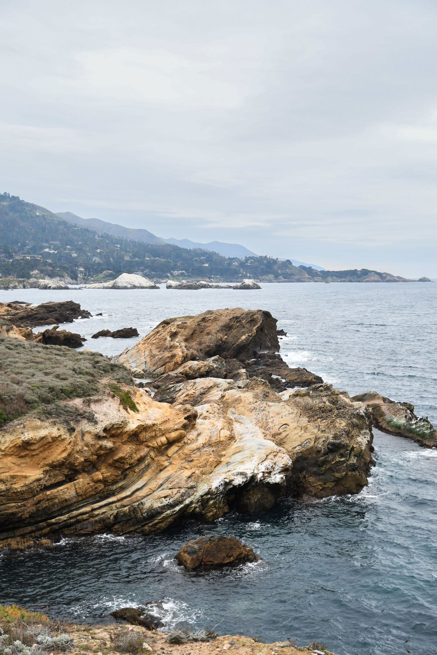 Rocky coastal cliffs overlooking the Pacific Ocean on a cloudy day.