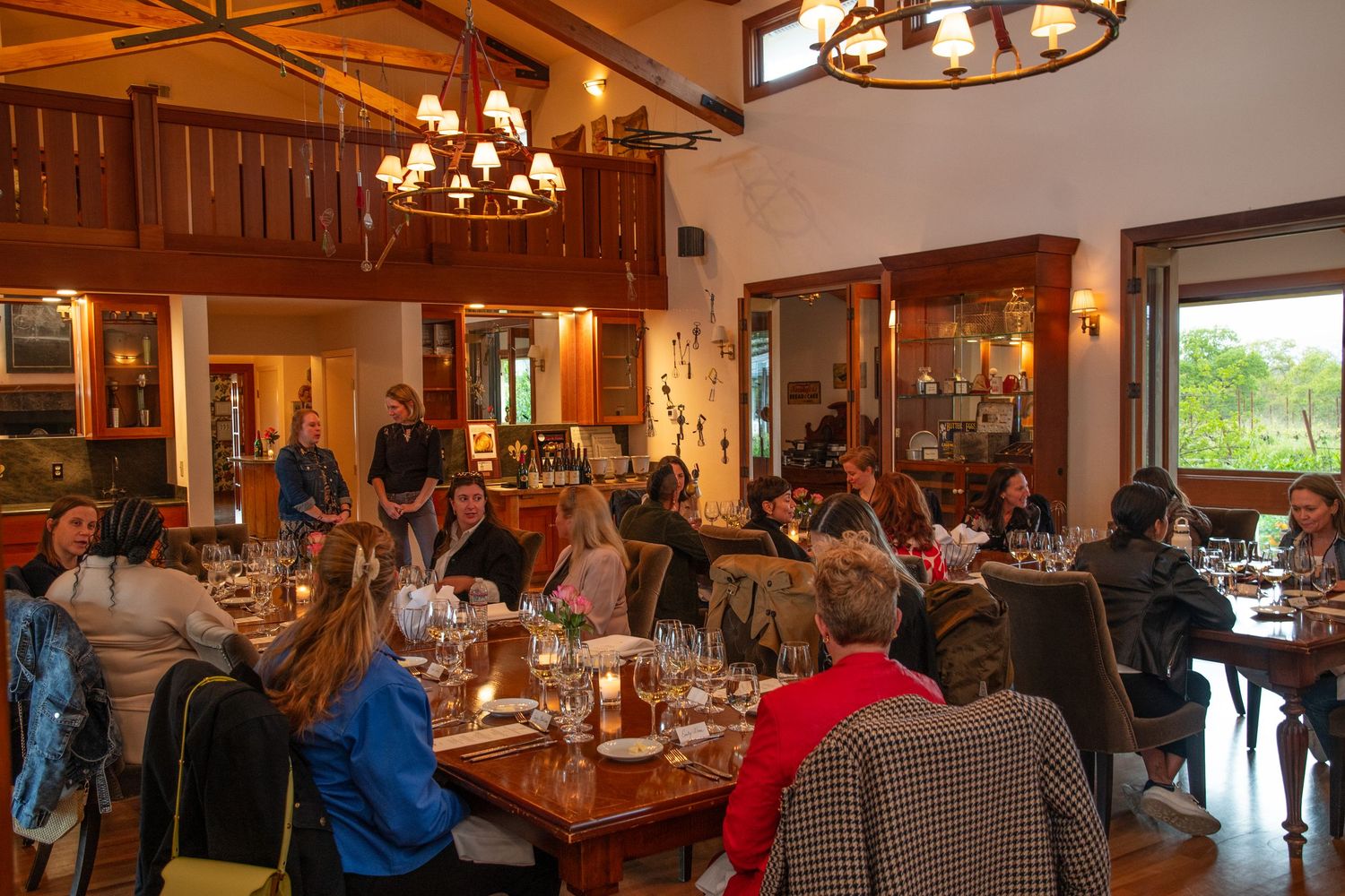 Guests gather in a rustic dining room with wooden beams and chandeliers for a special event.