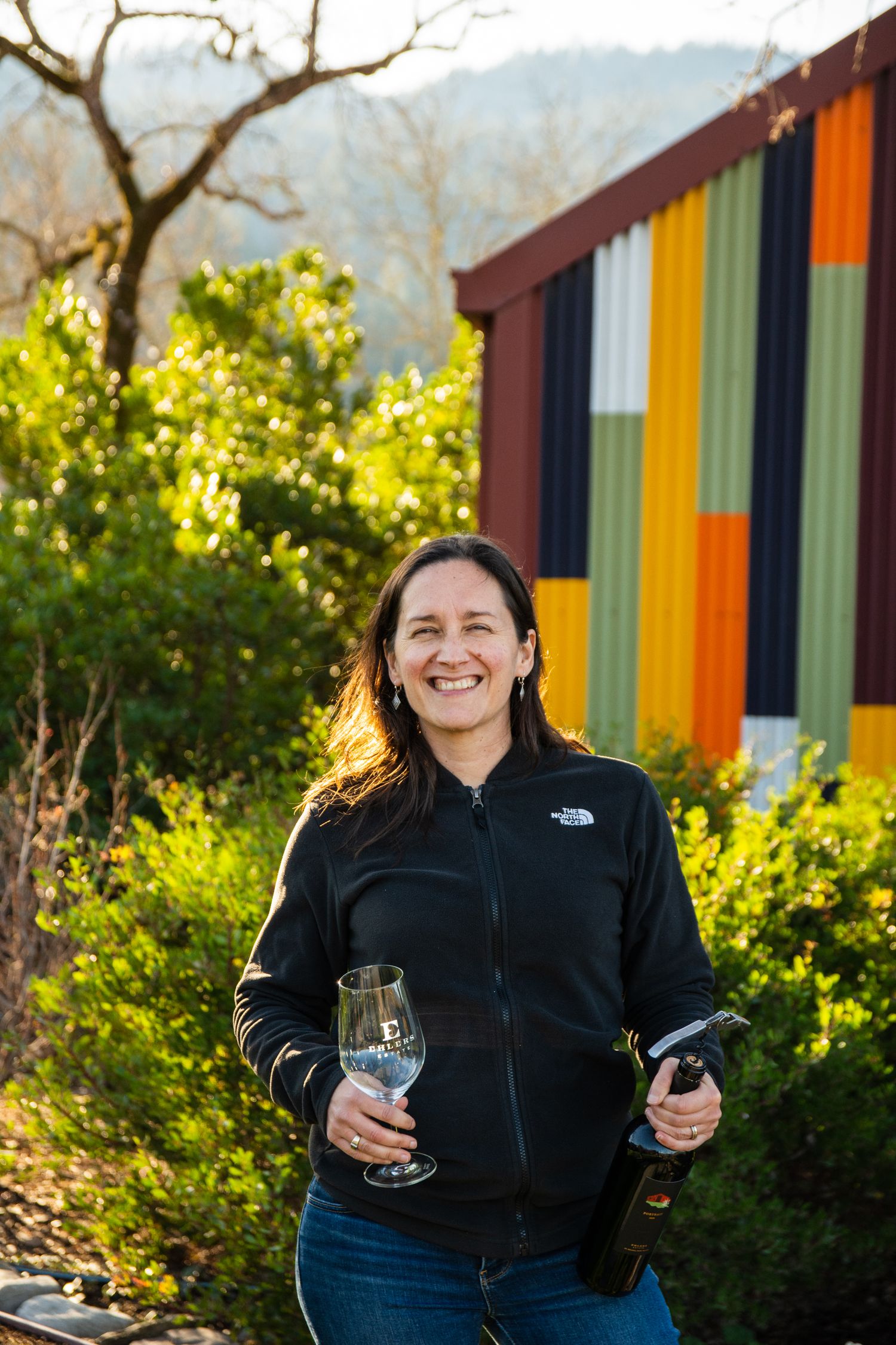 Colorful striped wall creates vibrant backdrop at outdoor winery seating area.