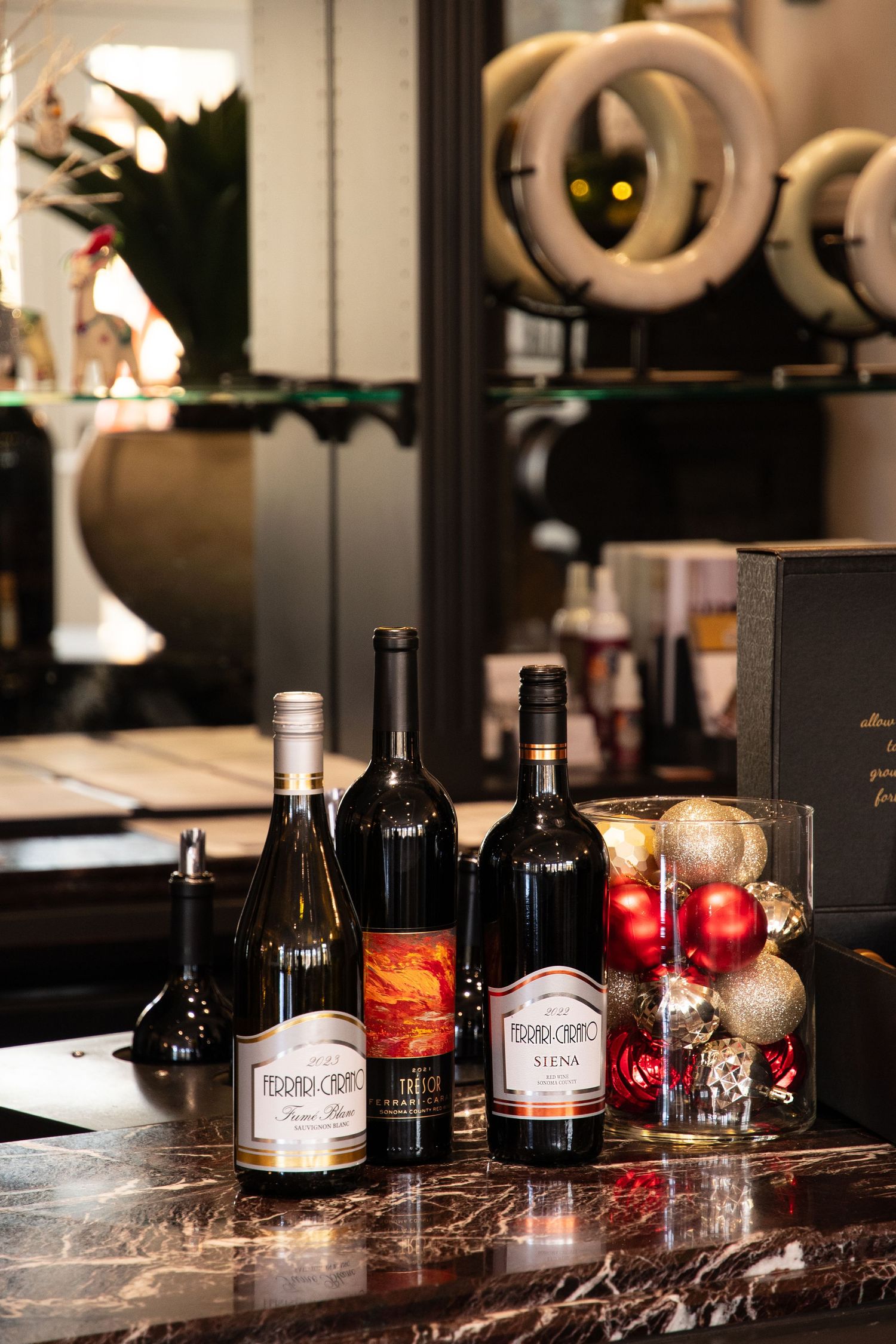 Collection of wine bottles displayed on a marble counter with holiday decorations.