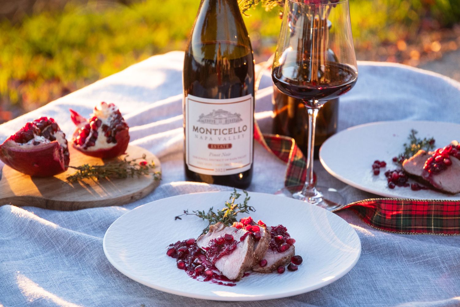 Elegant table setting with wine and food plates arranged in warm natural lighting.