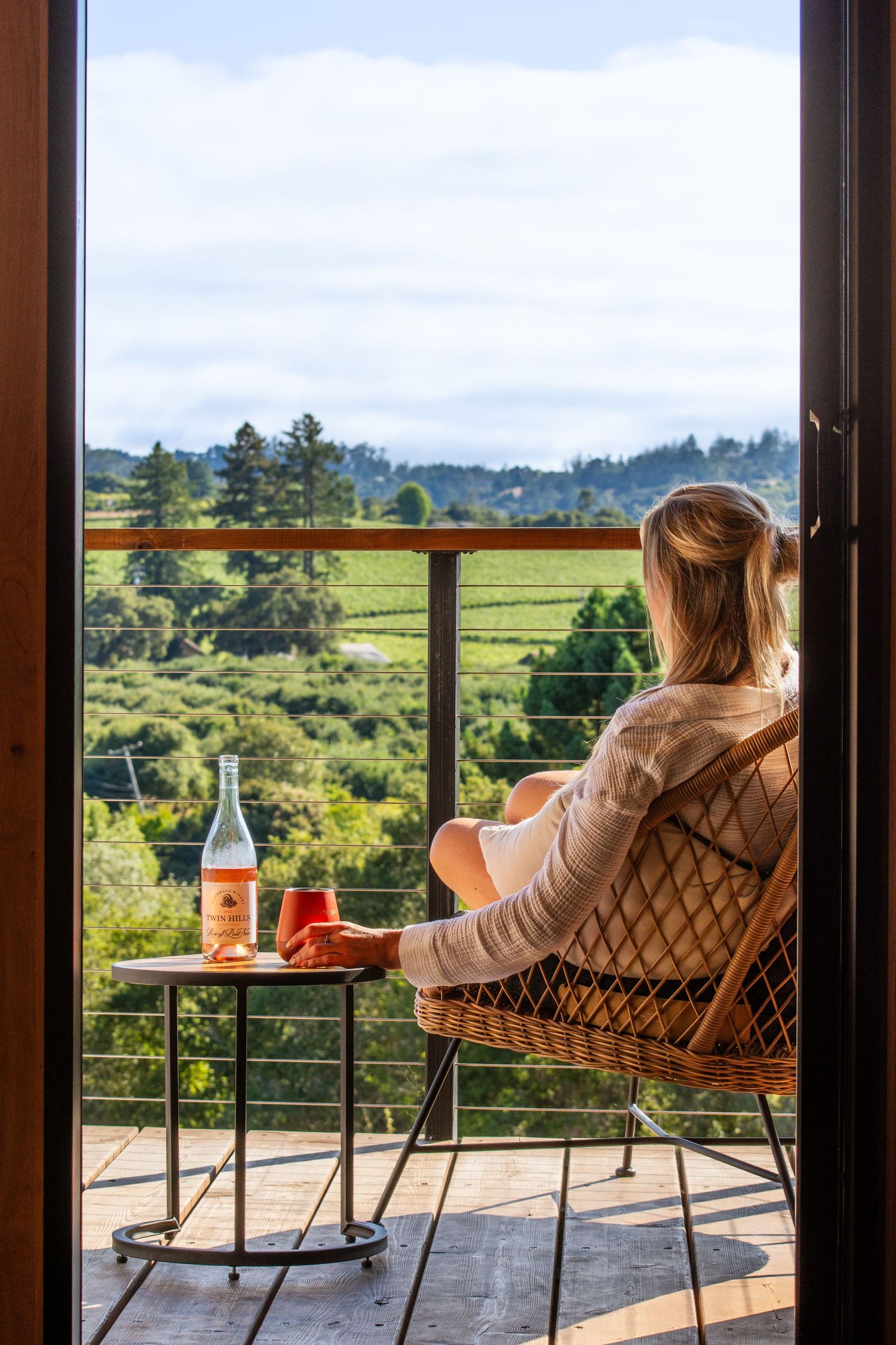Scenic vineyard view from a balcony with comfortable seating and refreshments on a side table.