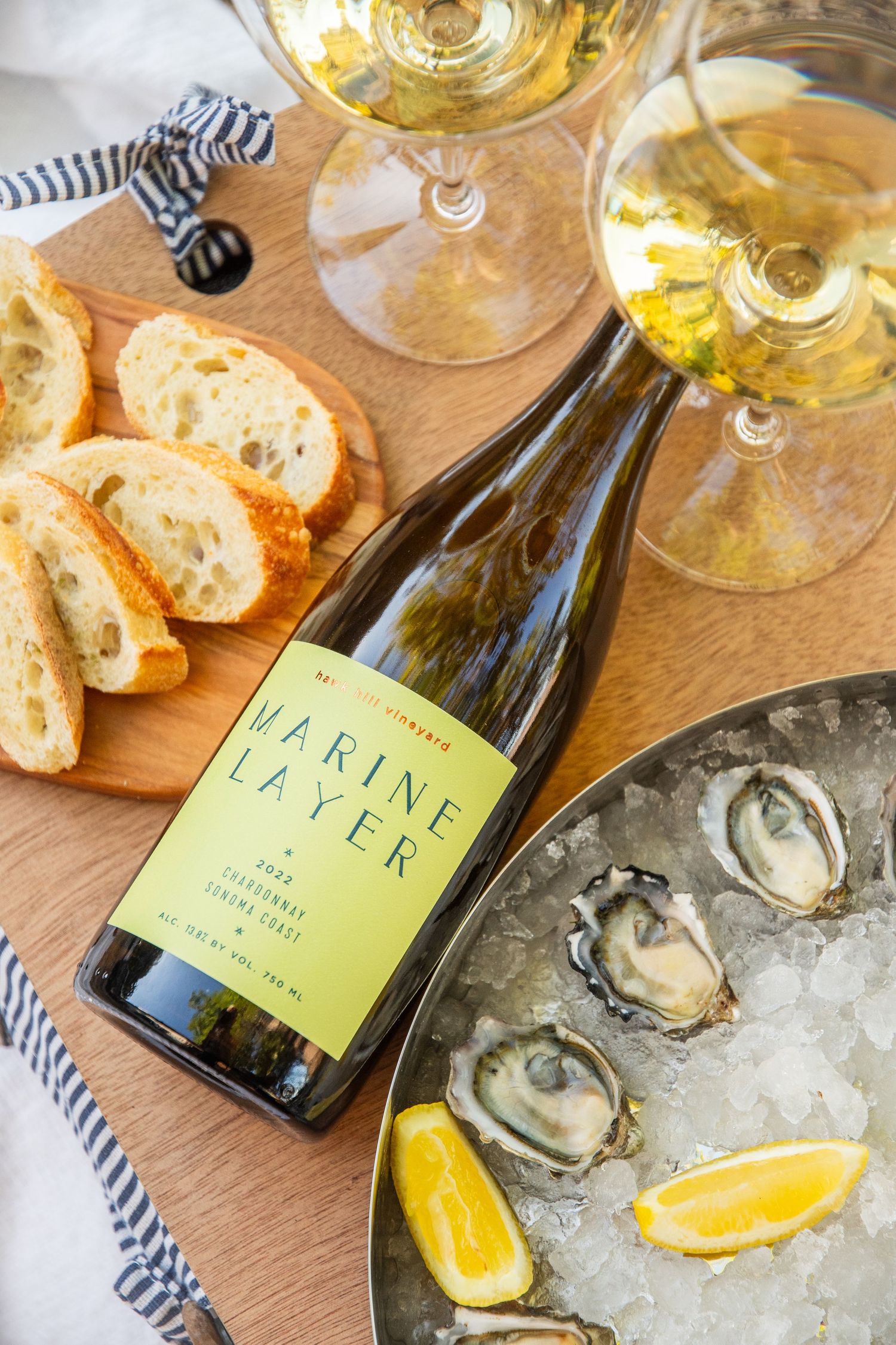 Fresh oysters on ice served with lemon wedges alongside bottles of white wine.
