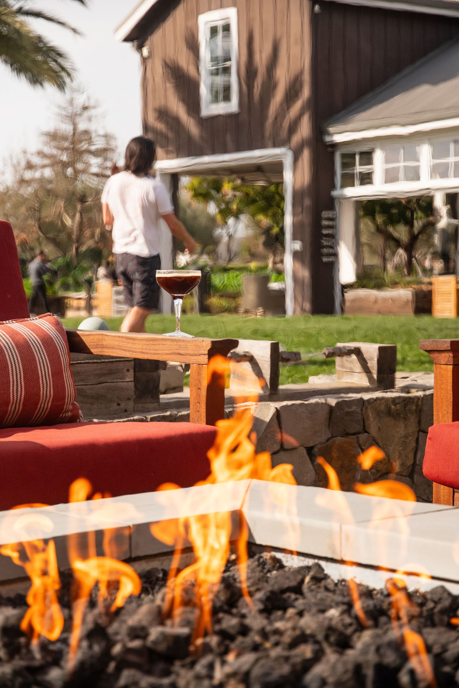 Outdoor patio seating area with wooden furniture and fire pit feature.