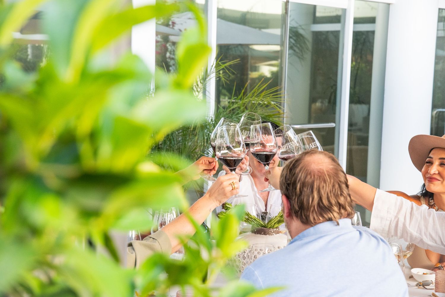 Group raising wine glasses in celebratory toast outdoors.