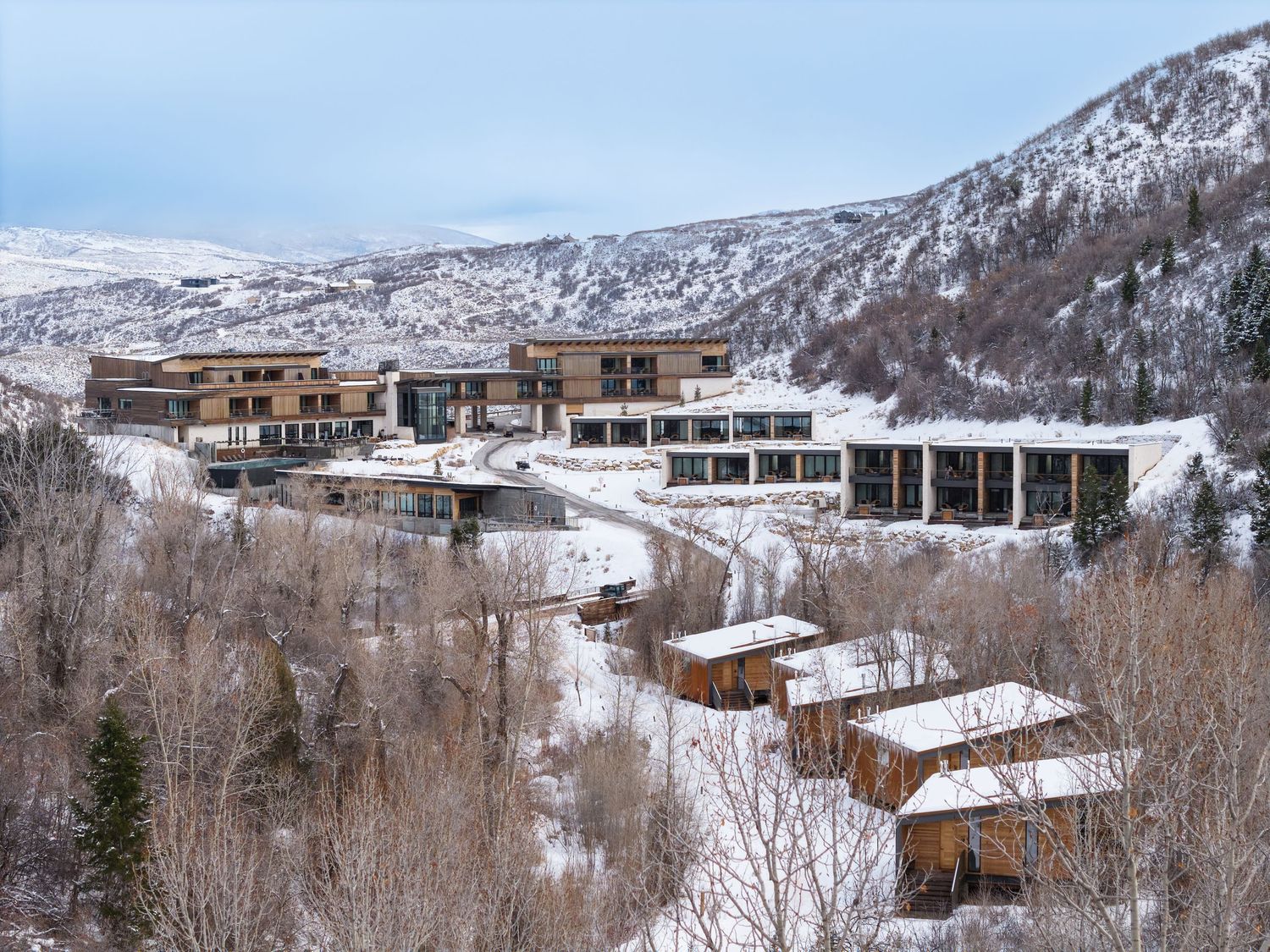 Snow-covered mountain resort with modern architecture nestled among winter trees on a hillside.