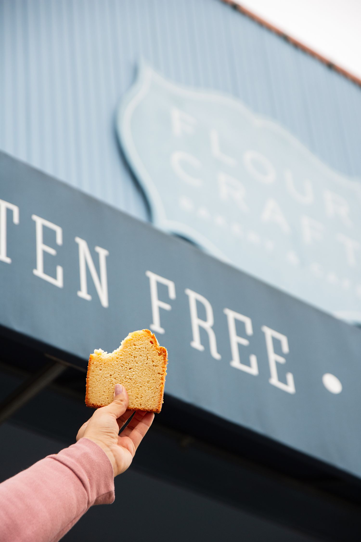 Close-up of a golden brown cookie or biscuit held against a light blue background.