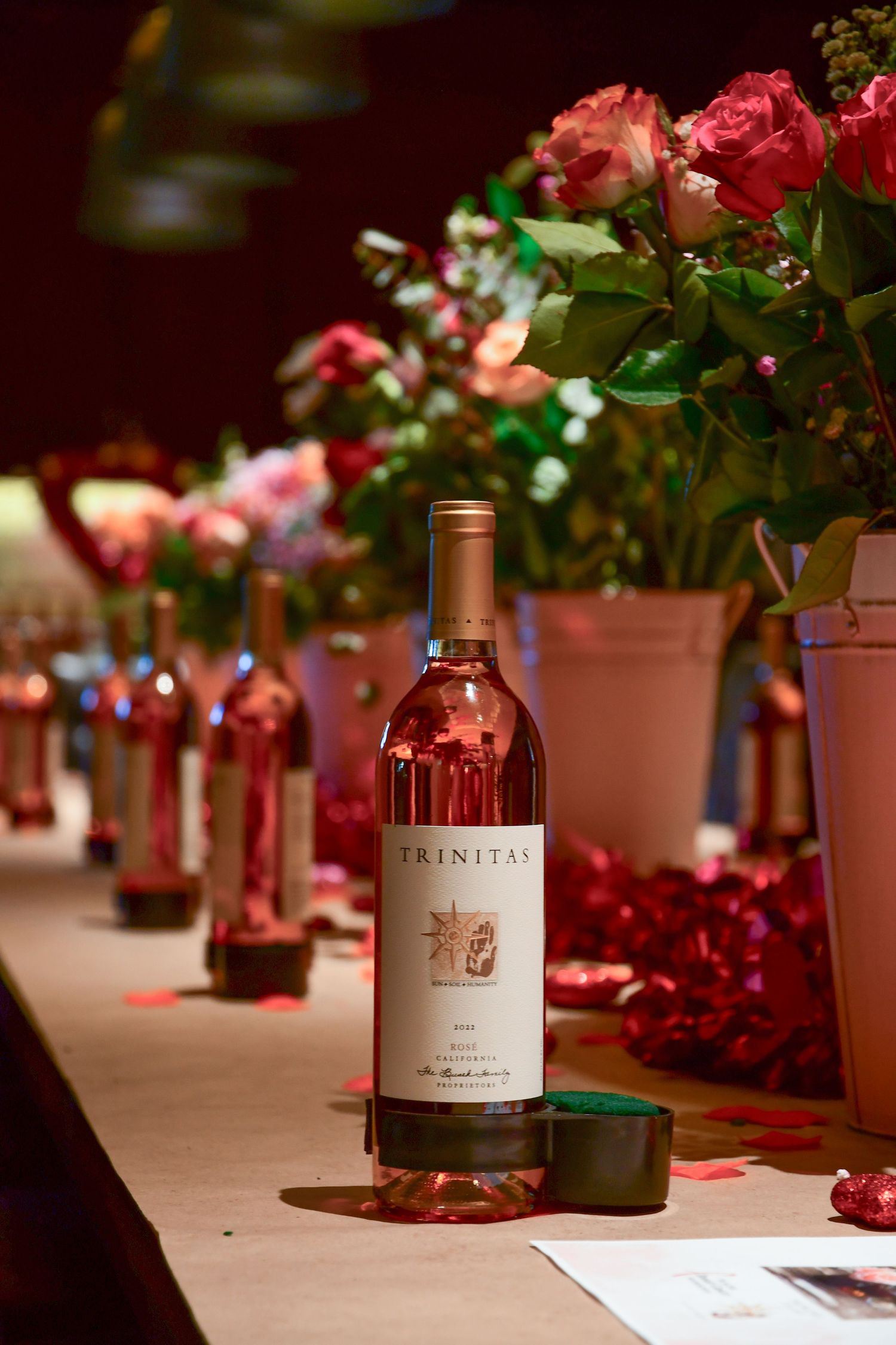 Wine bottles and floral centerpieces arranged on an elegant table setting with soft lighting.