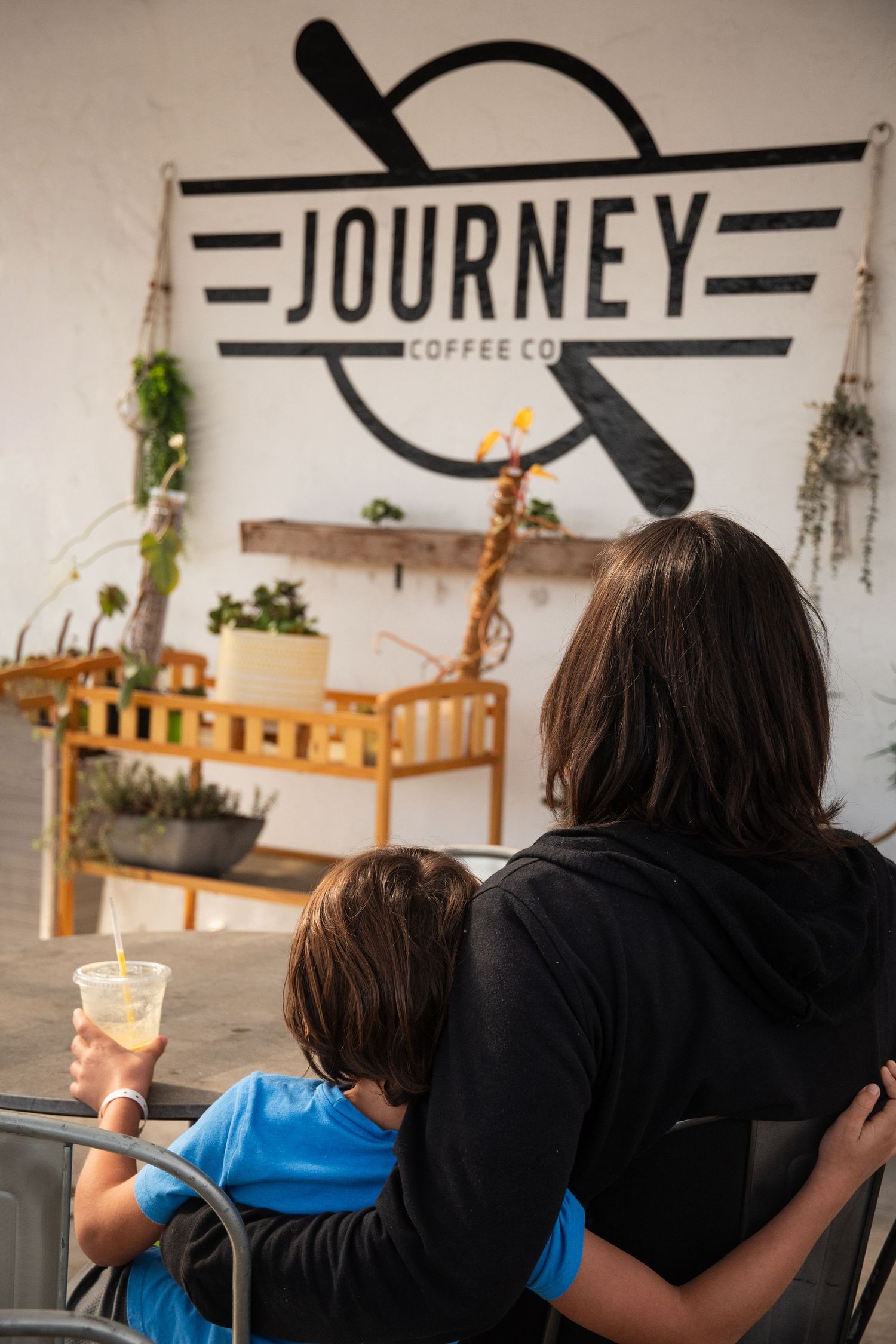 Journey Coffee Co logo and signage displayed on white wall with wooden bench below.