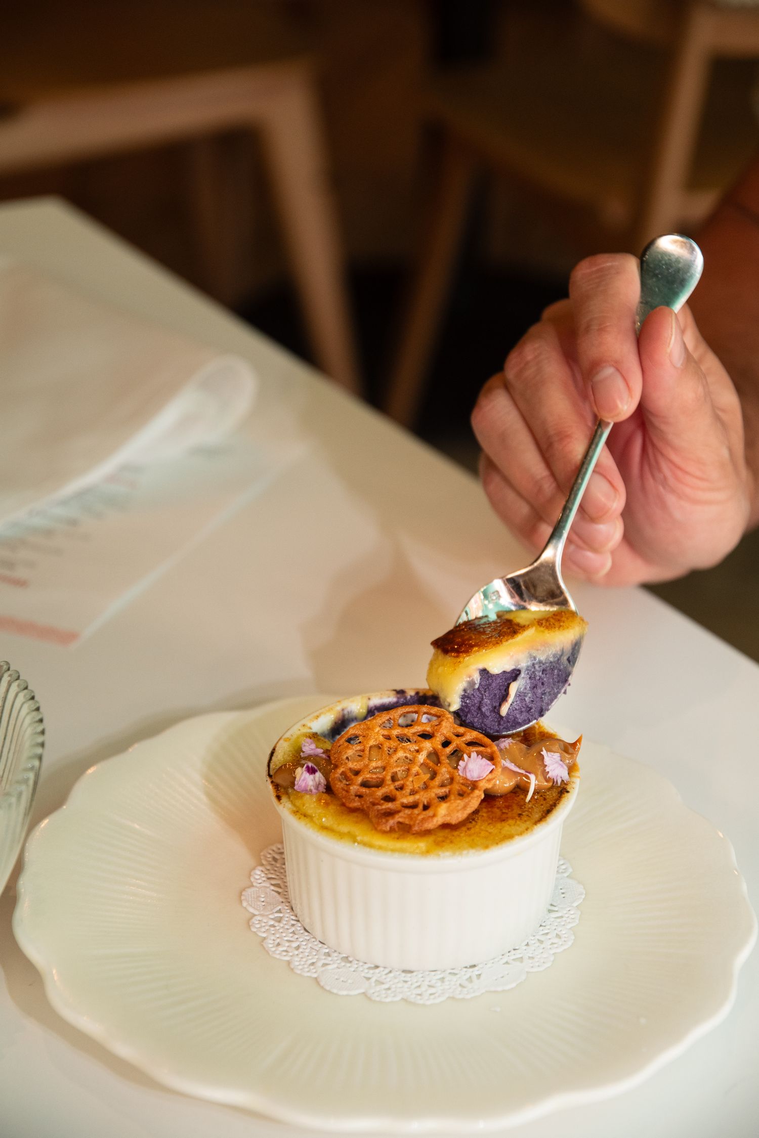 Elegant crème brûlée dessert being served on white plates with delicate garnishes.