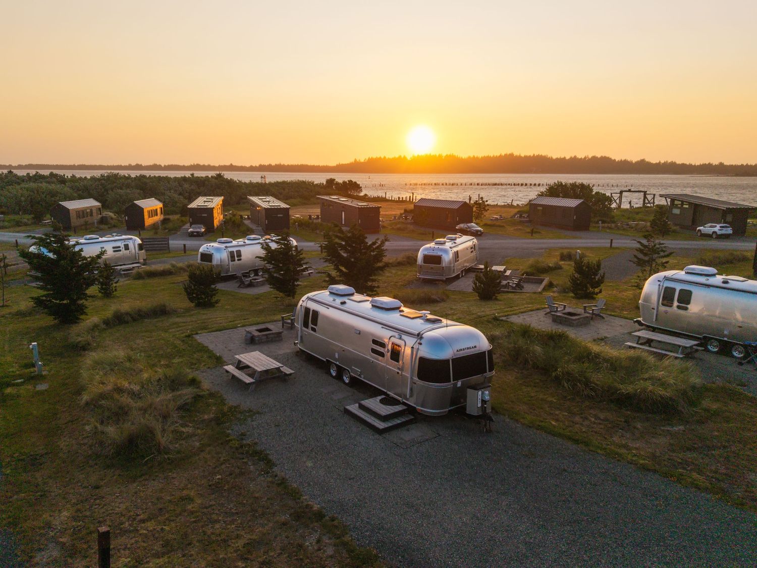 RVs and campers parked at a scenic coastal campground during golden hour.