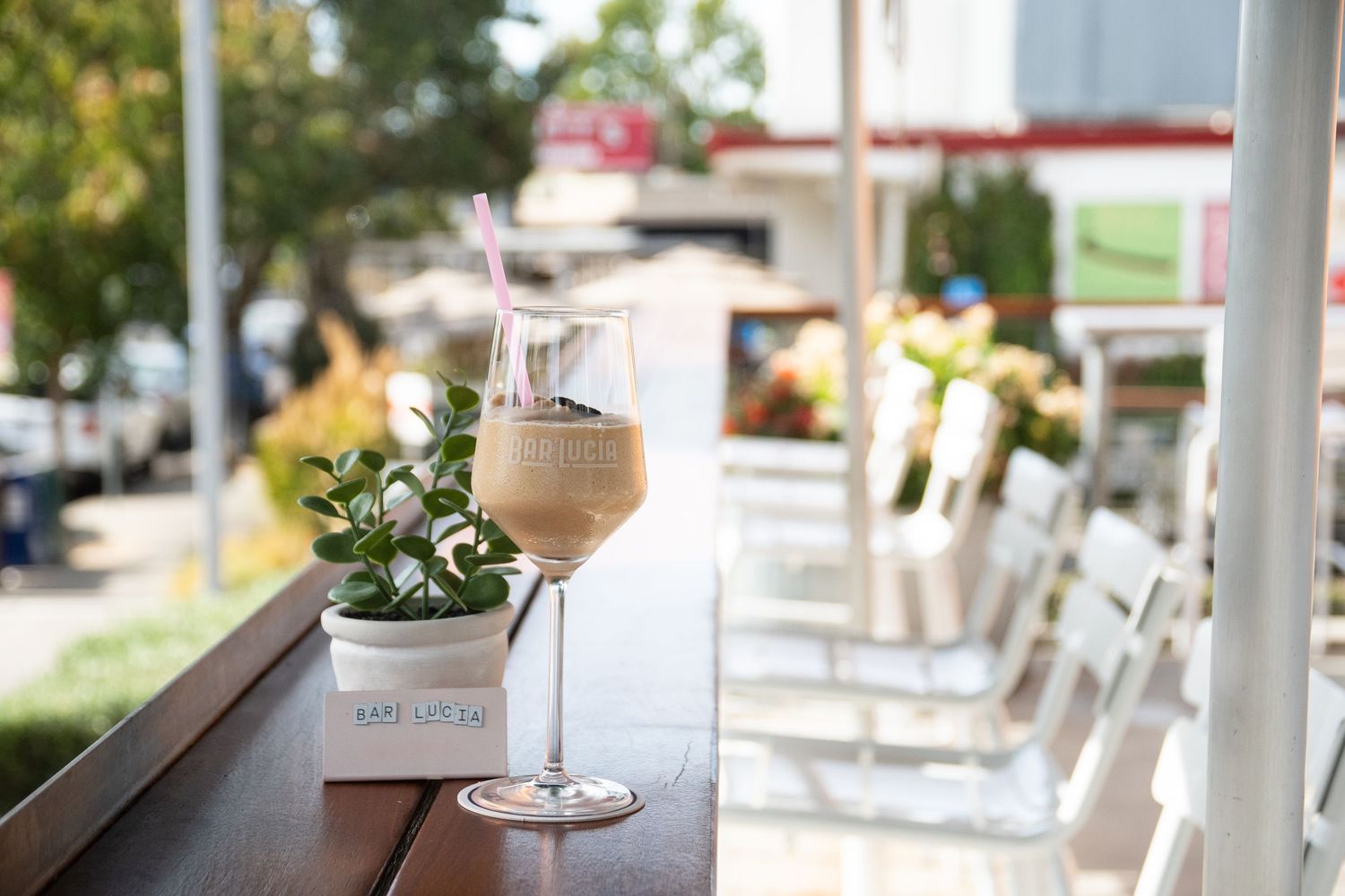 Glass of rose wine on outdoor patio with blurred greenery in background.