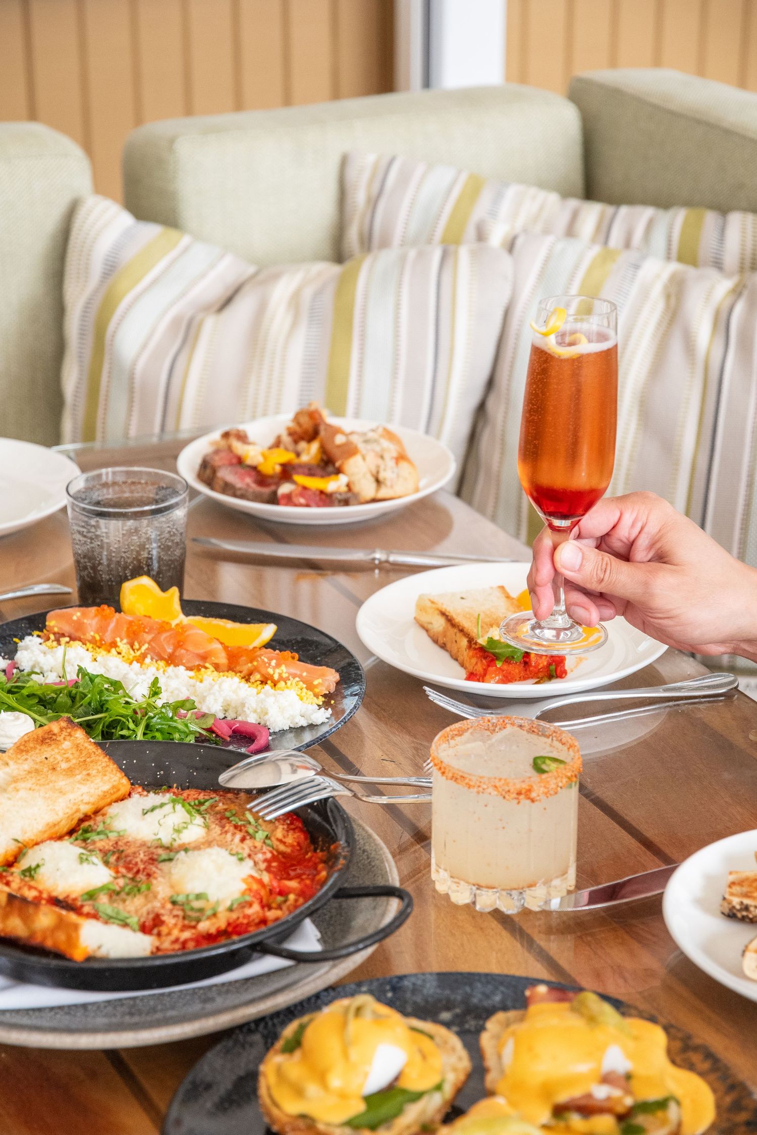 Multiple plates of brunch dishes including shakshuka and eggs benedict arranged on a dining table.