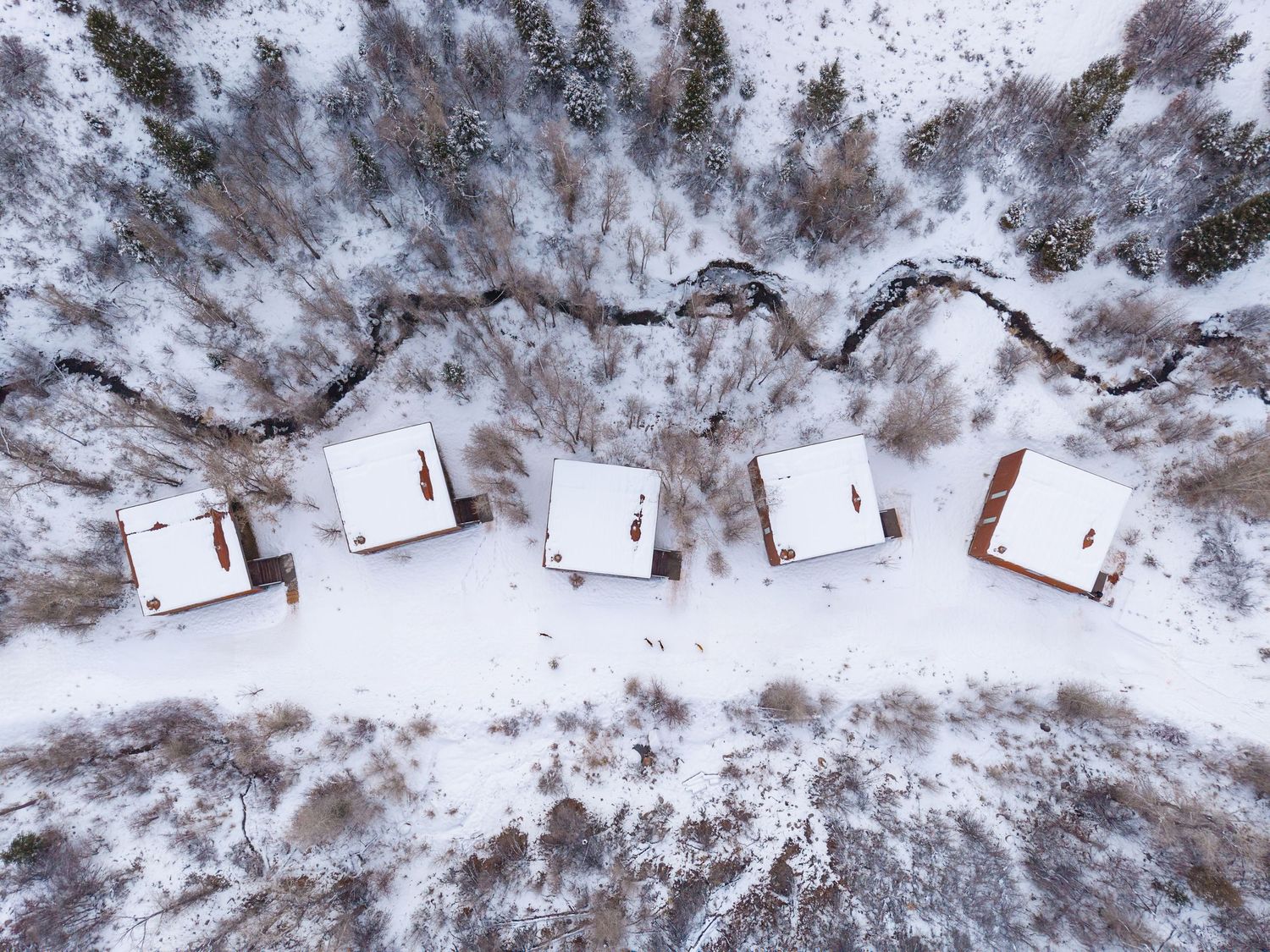 Aerial view of snow-covered buildings and terrain in a winter mountain setting.