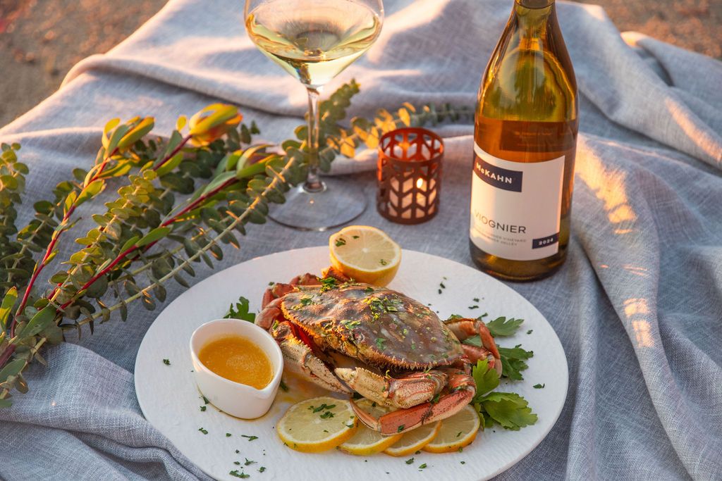 Beautifully plated crab dish with white wine and decorative lighting in background.