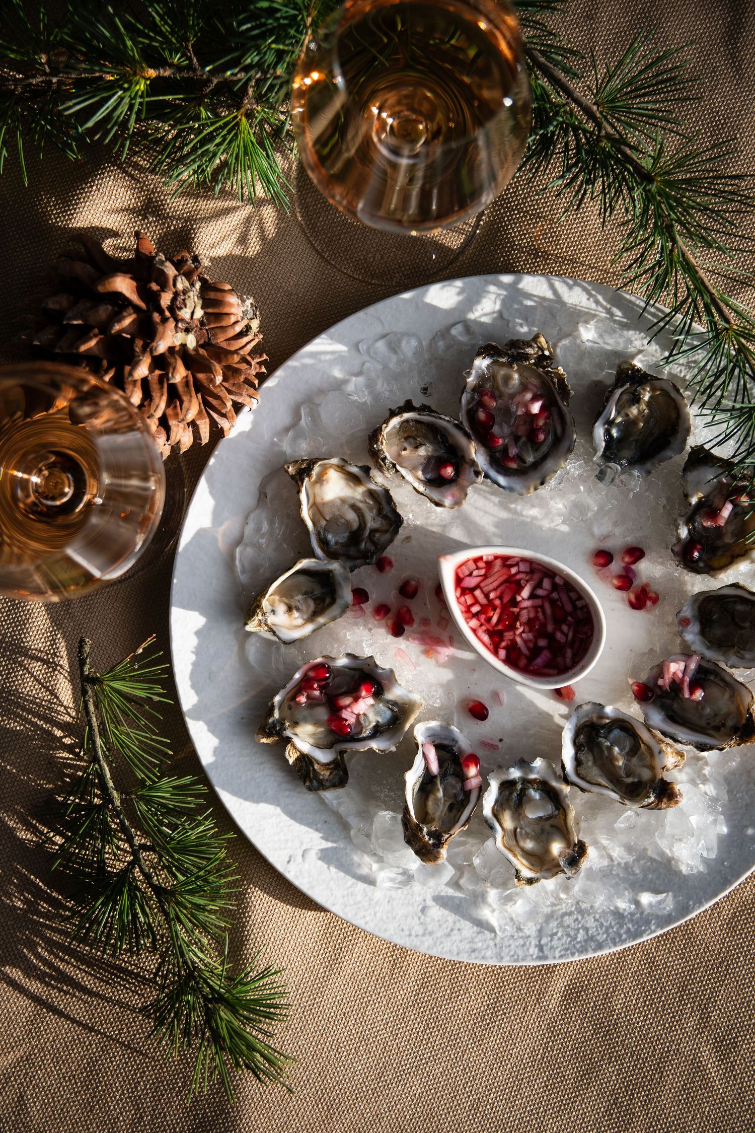 Freshly shucked oysters served on crushed ice with pomegranate garnish and rosé wine.