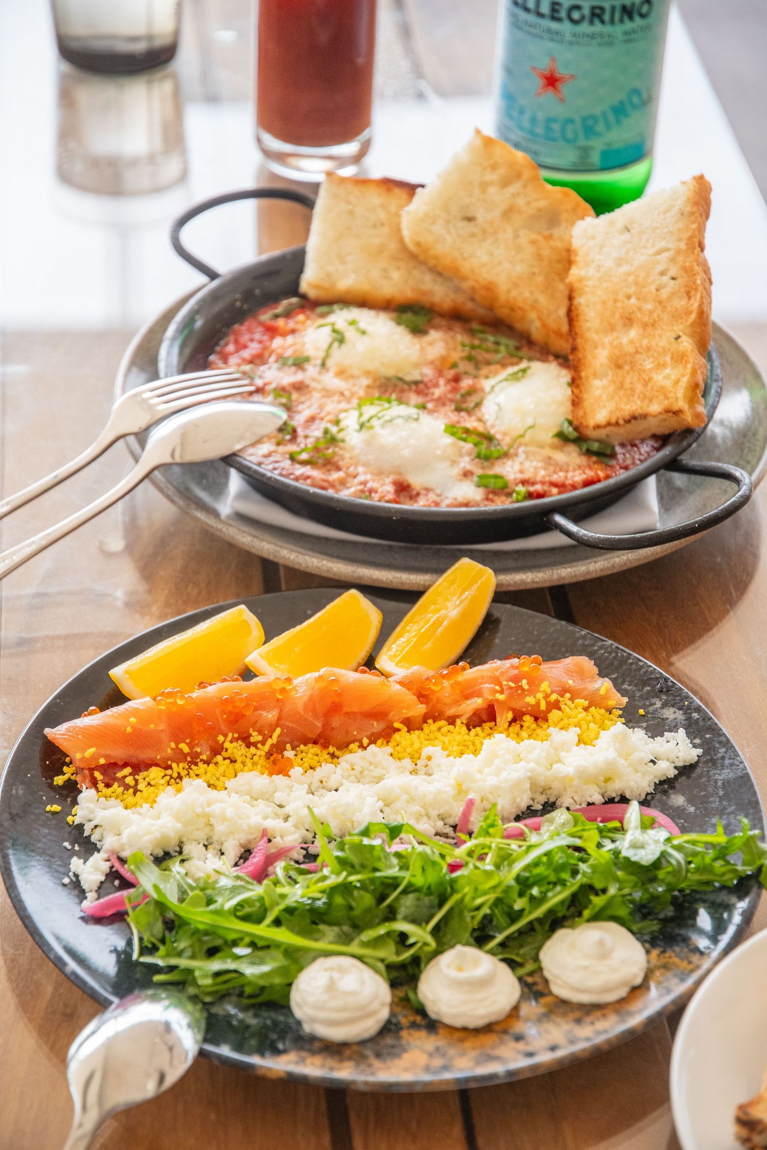 Colorful plated dishes featuring salmon, fresh greens, and sauces served on dark plates.