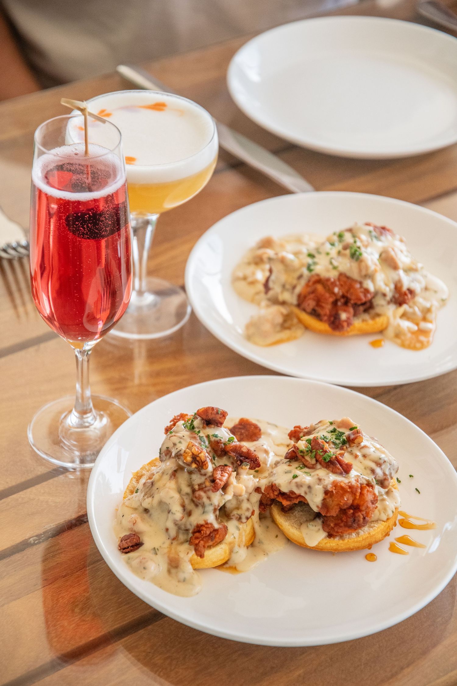 Creamy seafood dish with sauce and garnish served with red cocktail in upscale restaurant setting.