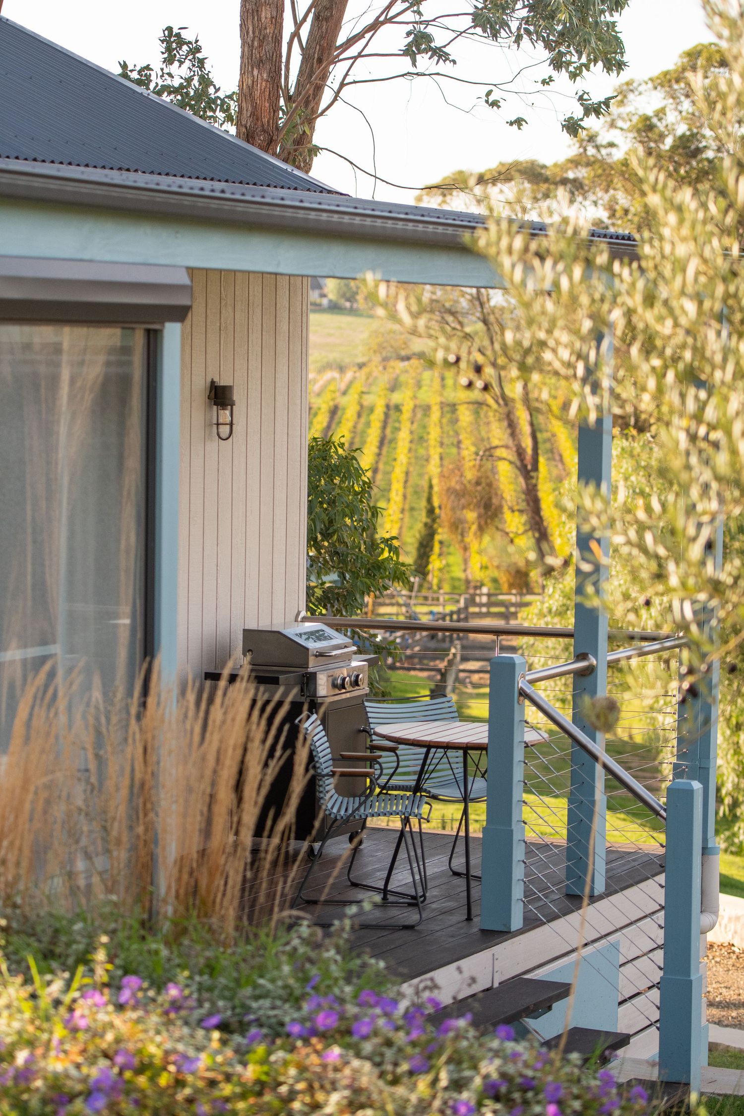 Rustic deck with outdoor seating overlooking vineyard at golden hour.