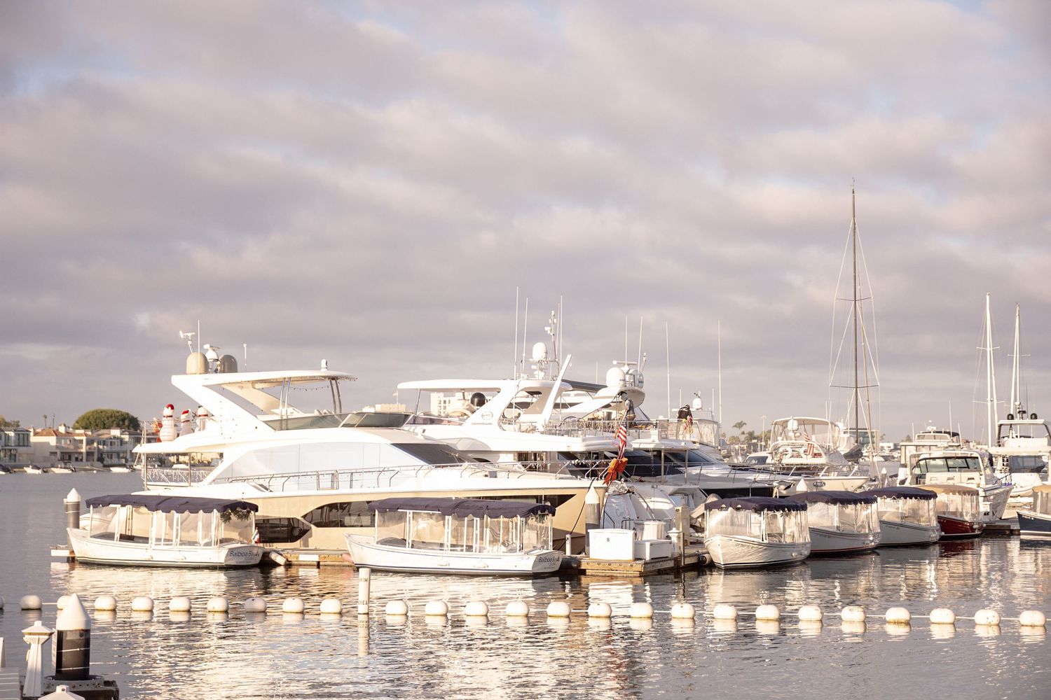 Marina filled with luxury yachts and boats docked along white piers on a cloudy day.