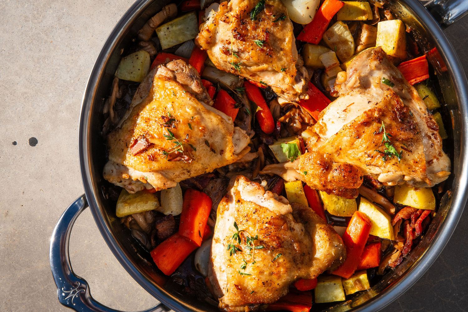 Roasted chicken thighs with colorful bell peppers and vegetables in a cast iron skillet.