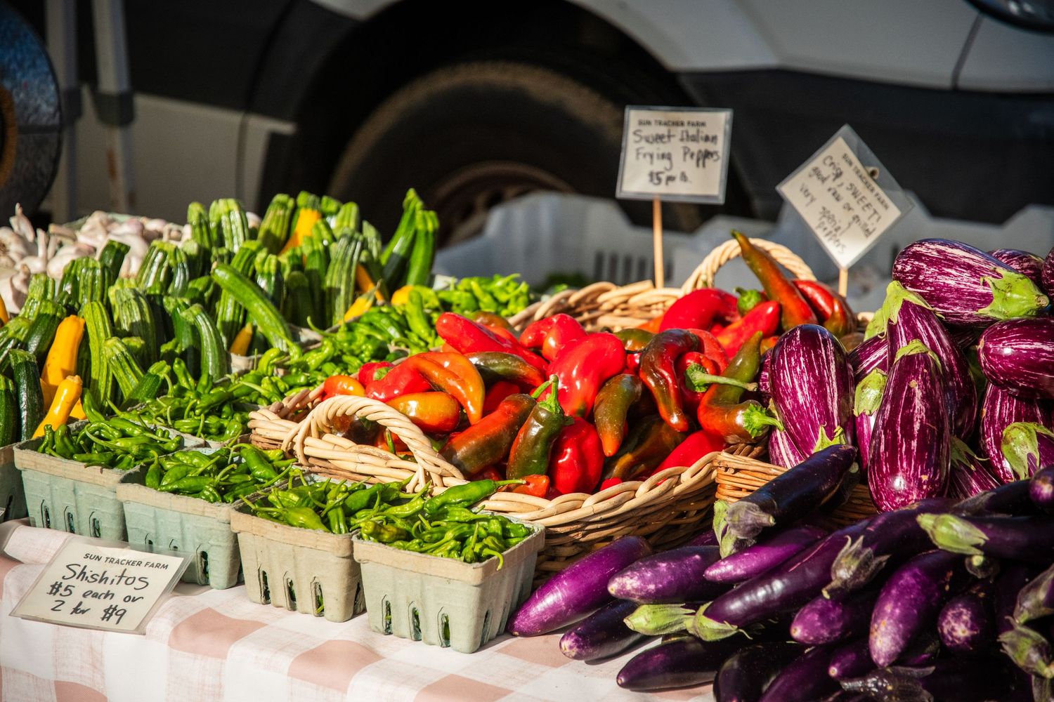 Fresh colorful vegetables including peppers and eggplants displayed at a market stand.