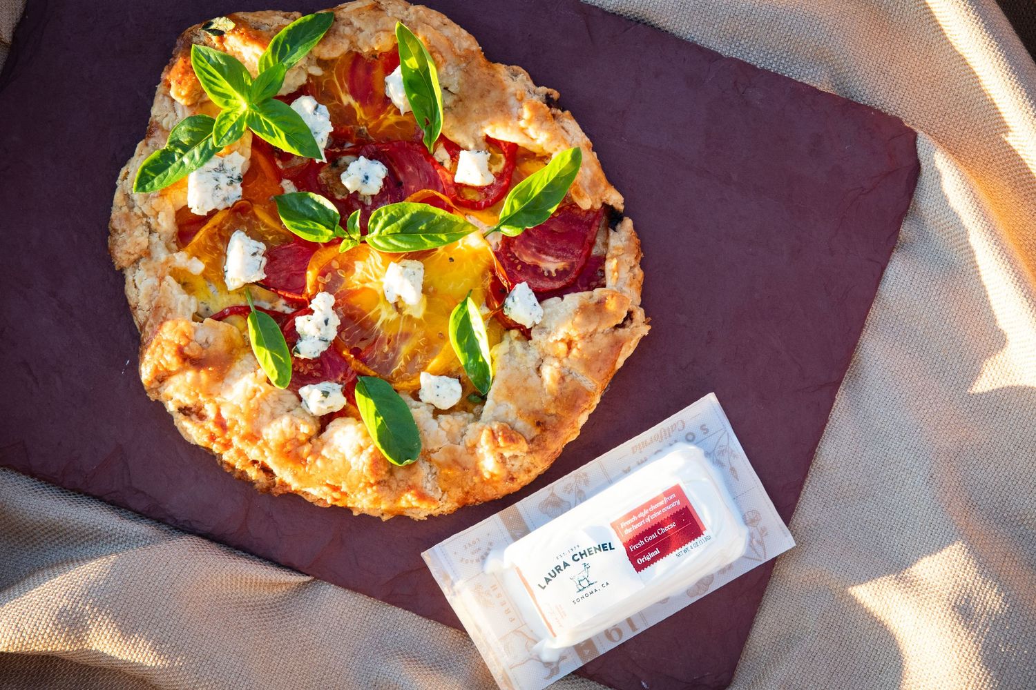 Gourmet flatbread pizza with fresh toppings and herbs served on purple placemat.