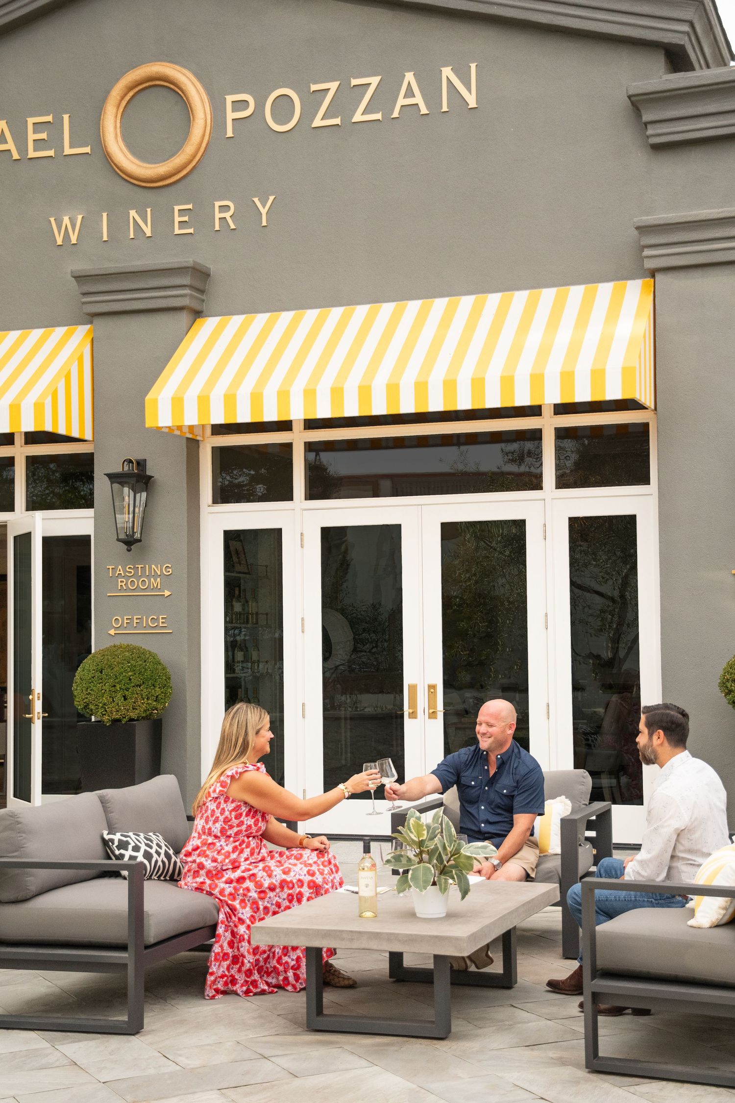 Michael Pozzan Winery storefront with yellow striped awnings and outdoor seating area.