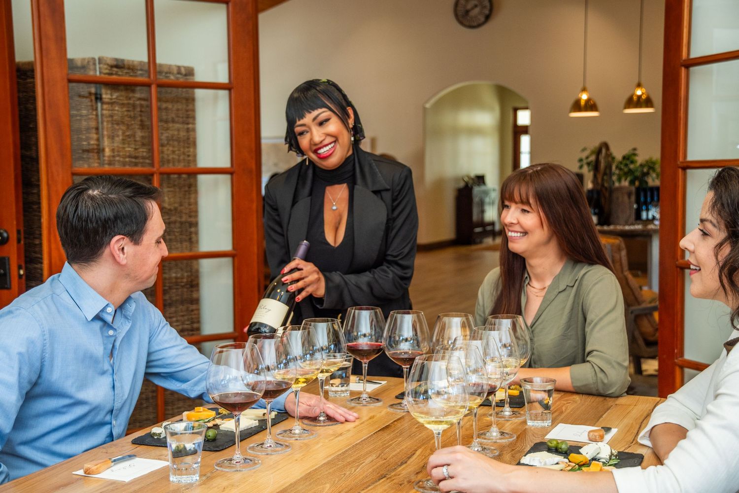 Friends sharing wine and laughter around a dining table indoors.