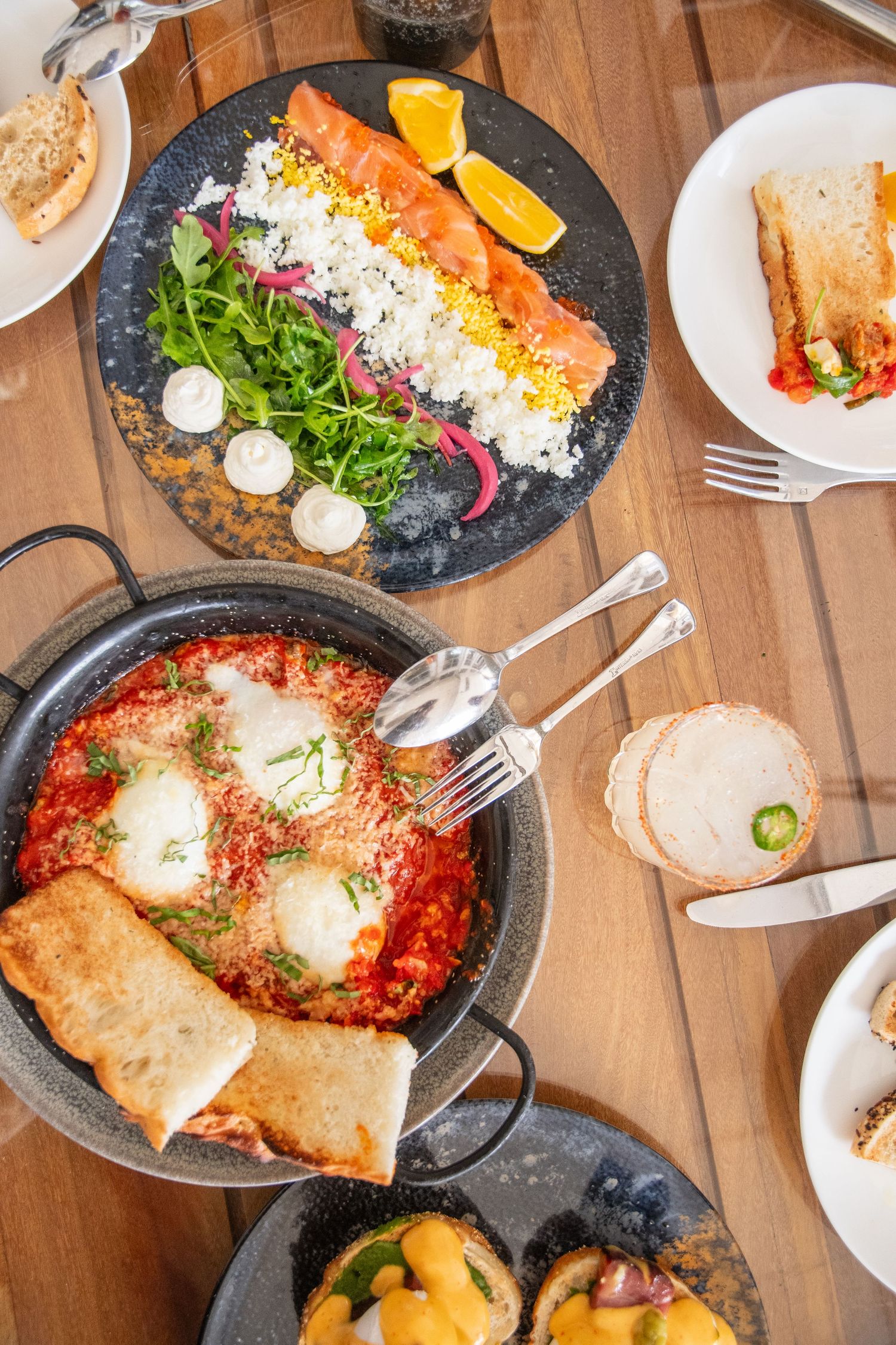 A spread of Italian dishes including shakshuka with poached eggs and crusty bread served in cast iron pans.