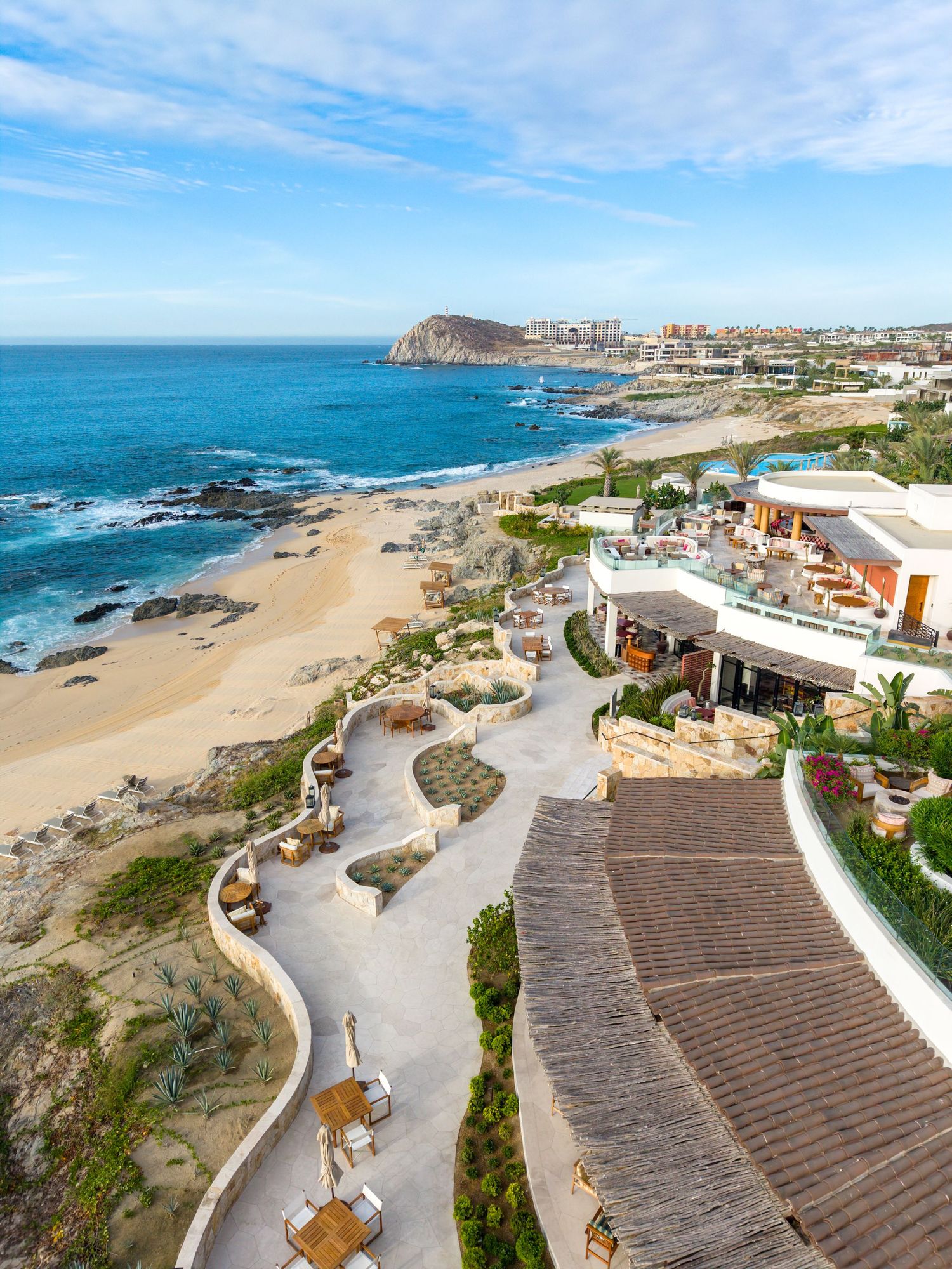Aerial view of a luxury beachfront resort in Los Cabos, Mexico, with sandy beach and rocky coastline.