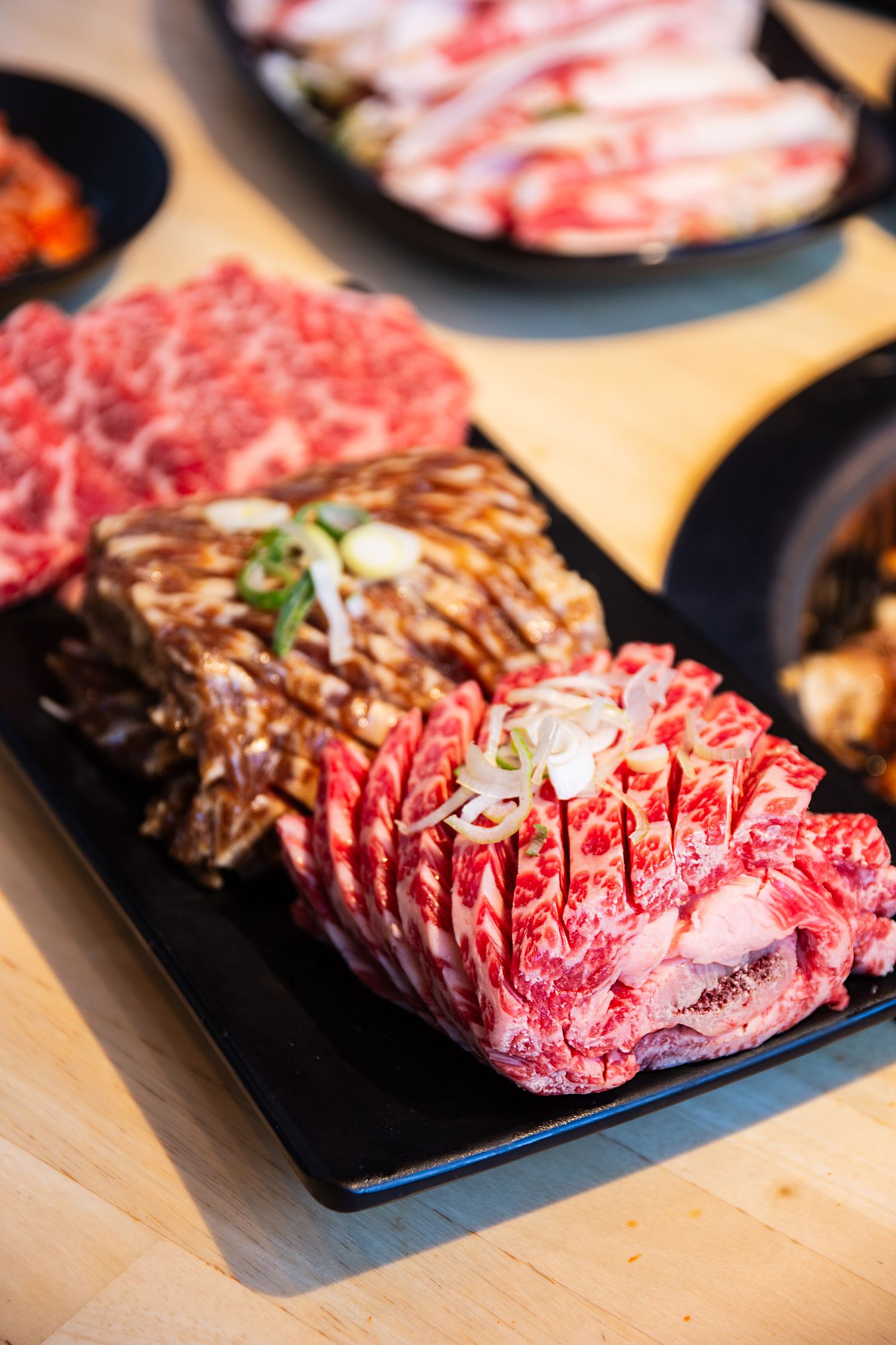 Beautifully arranged charcuterie board with thinly sliced cured meats on black plates.
