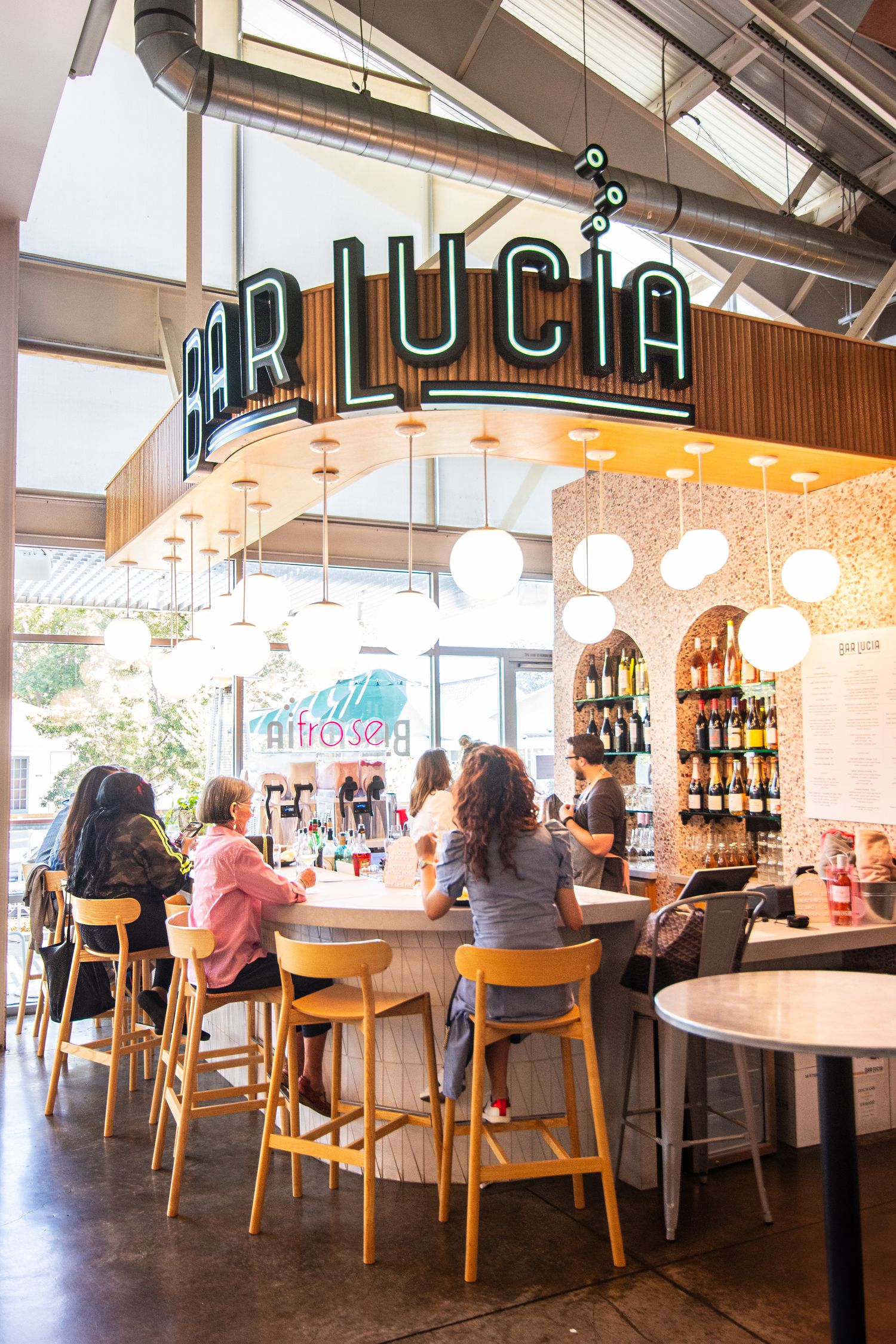 Modern restaurant interior with wooden chairs and bar seating under pendant lighting.