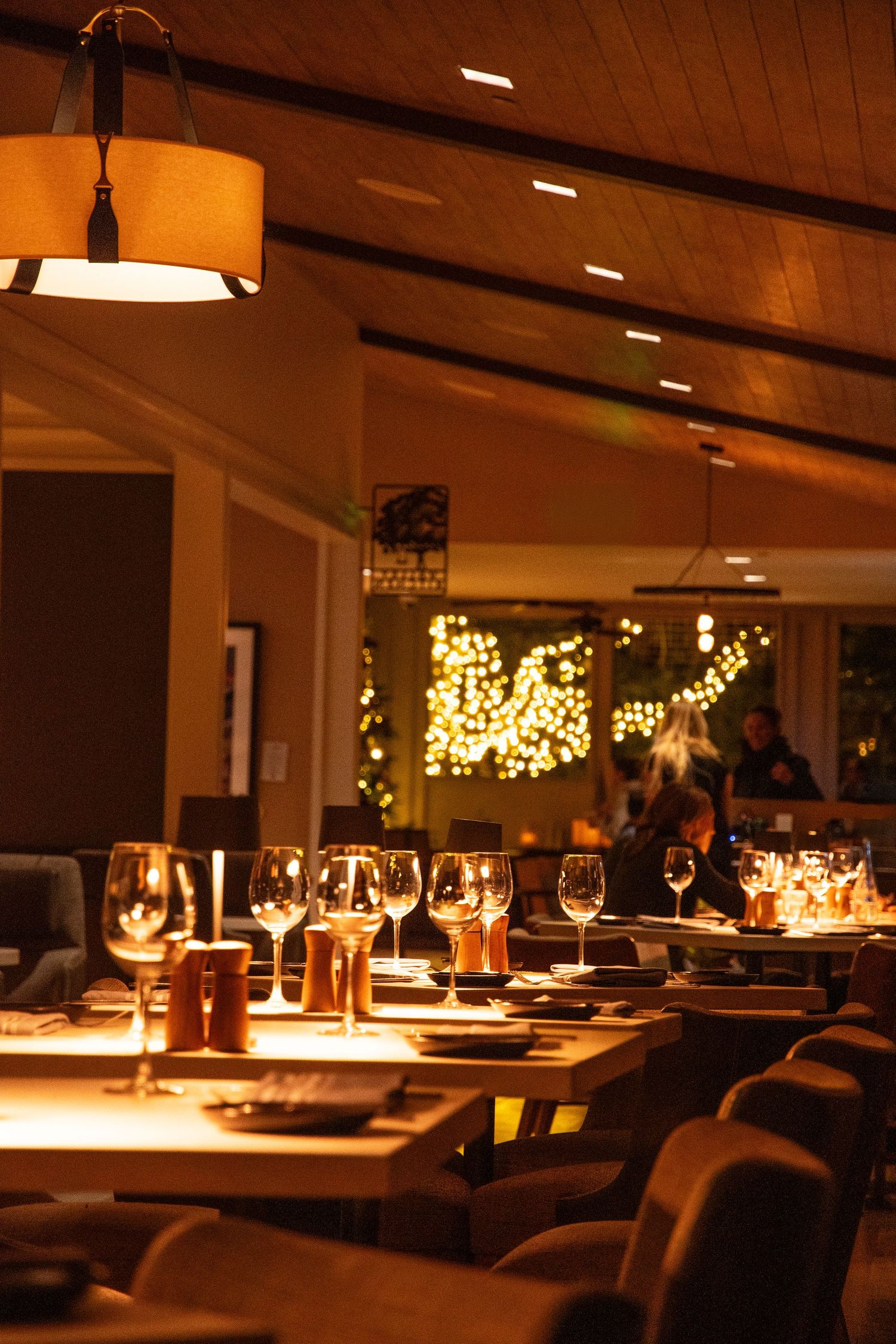 Intimate restaurant dining room with ambient lighting and wine glasses set for dinner service.