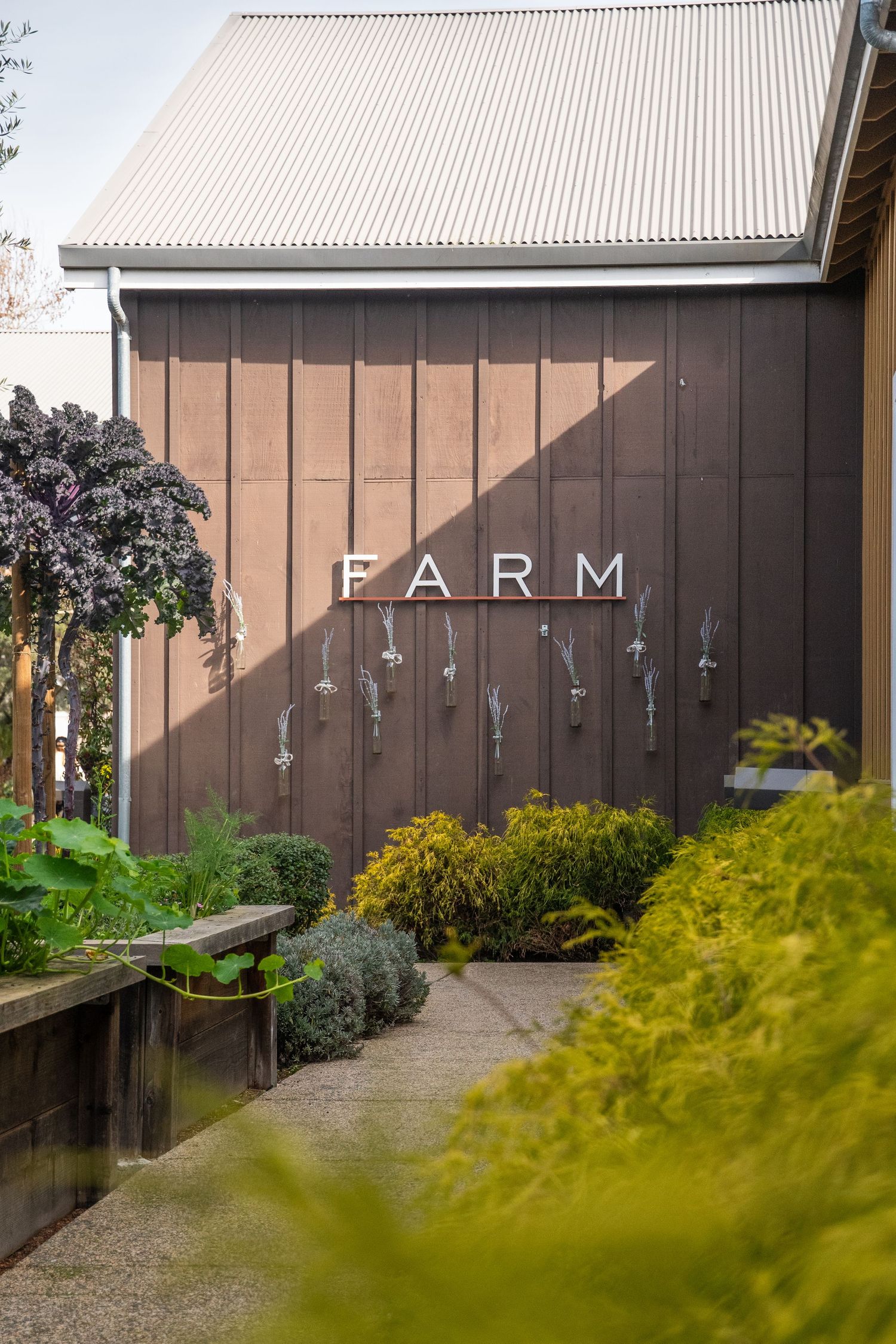 Brown building exterior with FARM signage and landscaped garden path.
