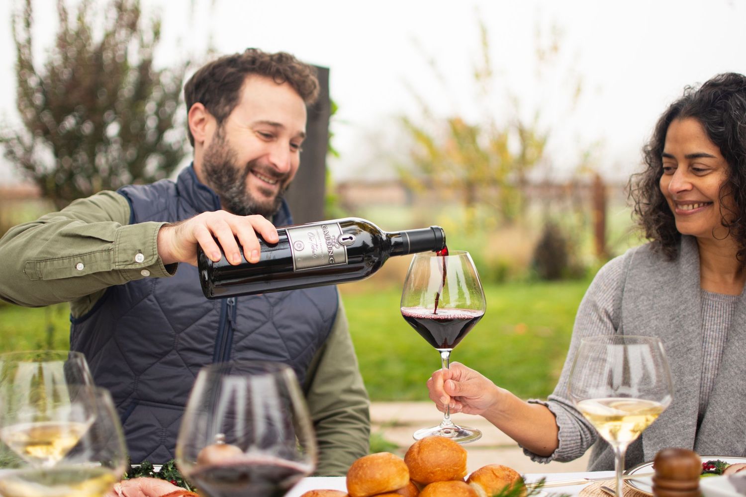 Friends enjoying wine and food at an outdoor gathering.