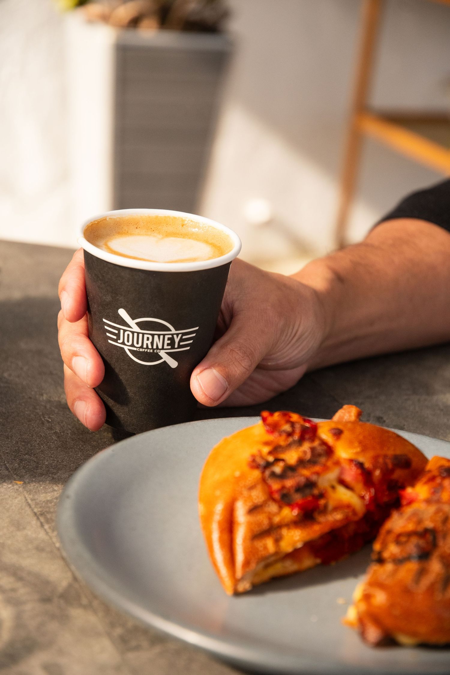 Journey Coffee Co cup next to plated pastry with warm lighting.