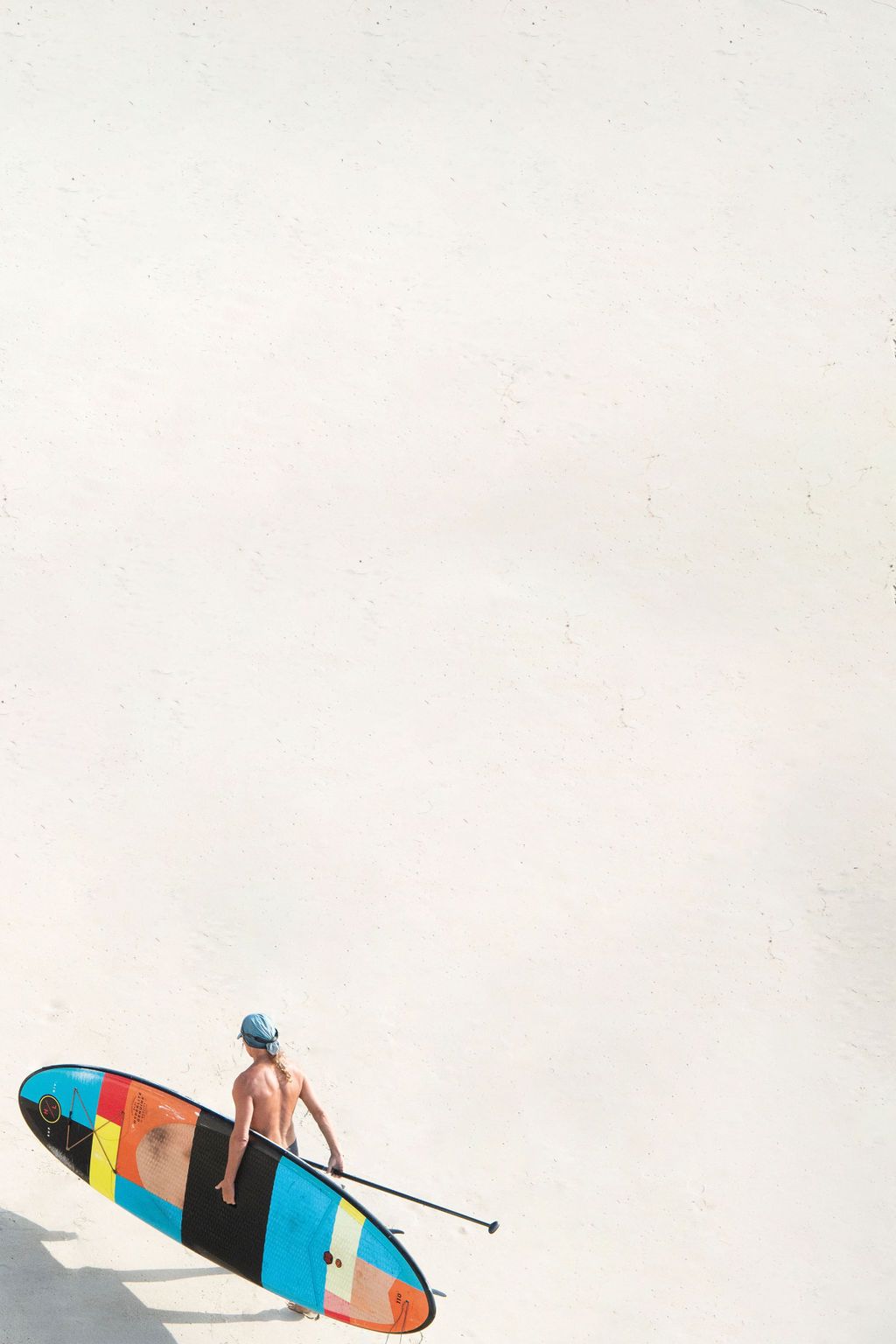 Colorful surfboard on a white background with vibrant geometric patterns and designs.
