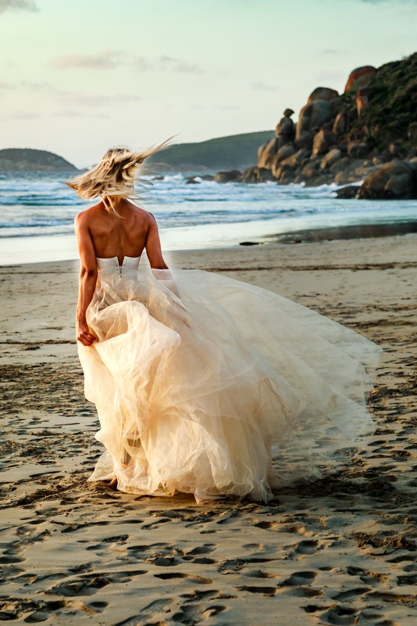 Flowing white dress billowing on beach at sunset.