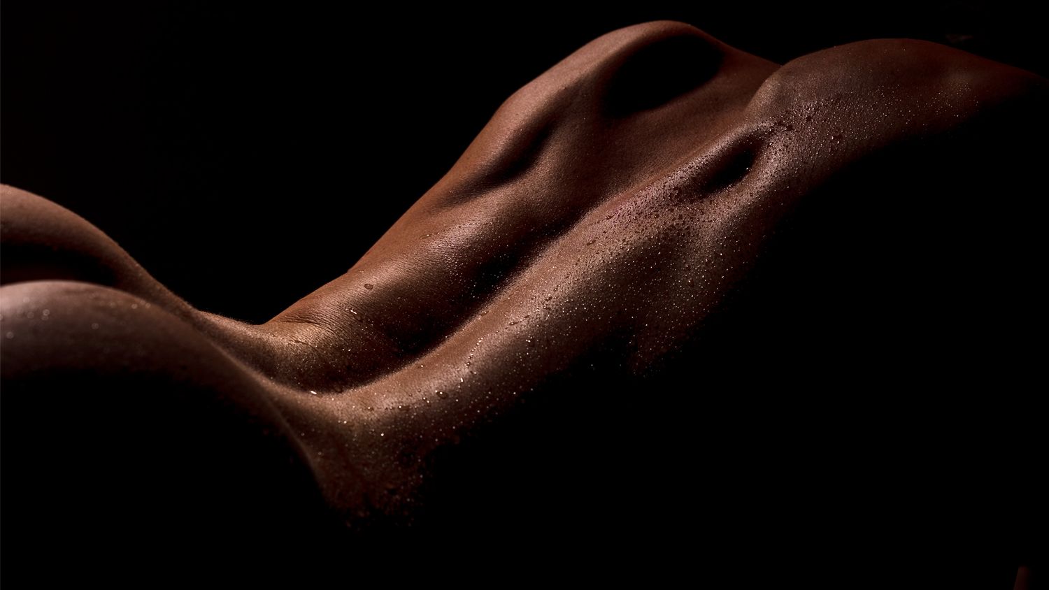 Close-up view of dark chocolate pieces arranged in a row on black background with dramatic lighting.