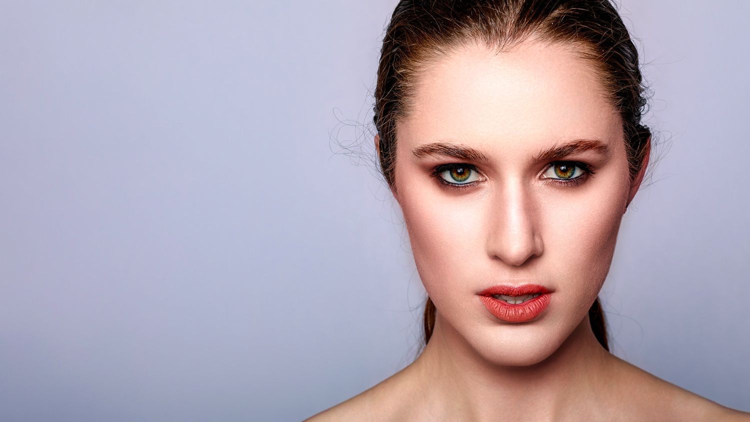 Beauty portrait with dramatic makeup and lighting against blue background.